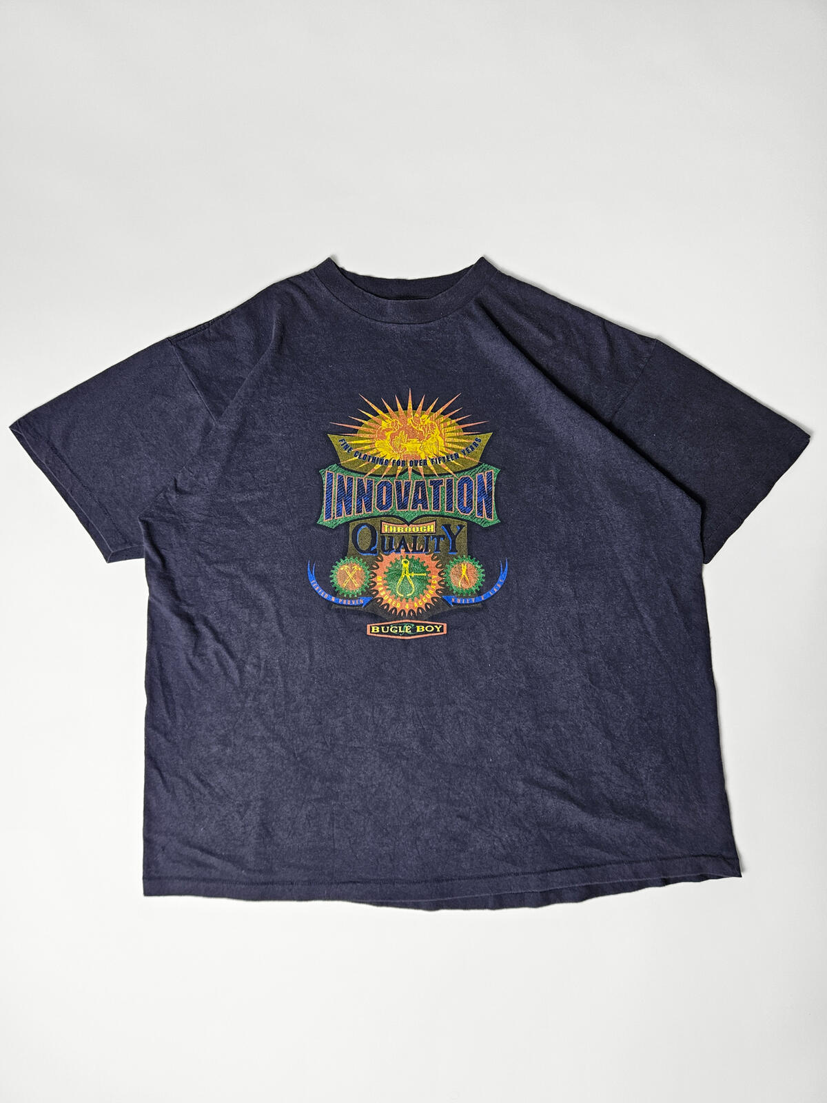 Flatlay van authentiek Bugle Boy 'Innovation Through Quality' promo T-shirt uit de jaren 90 – zeldzaam item voor retro workwear en streetwear liefhebbers