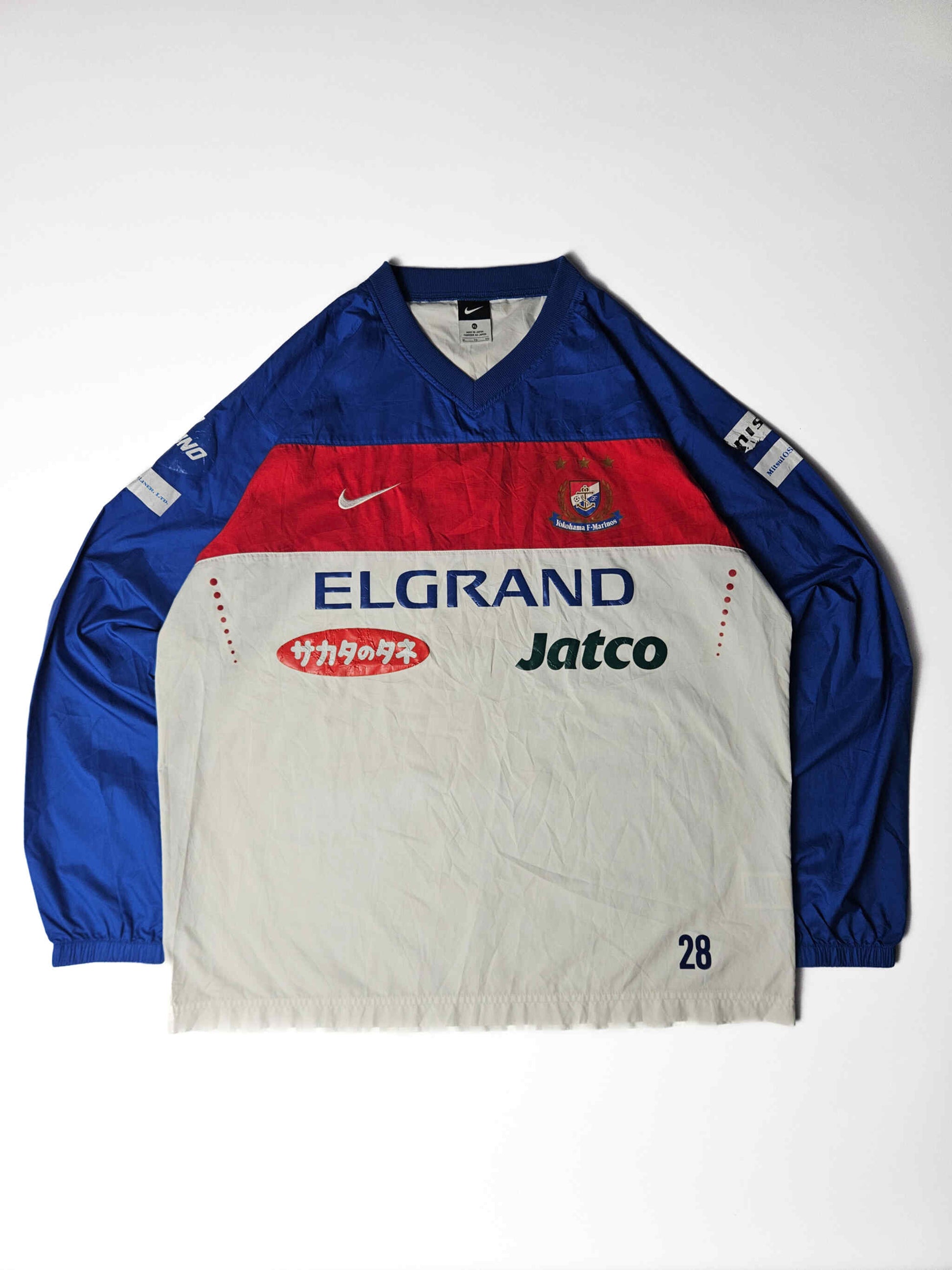 2000s vintage Nike Yokohama F. Marinos J-League voetbalshirt flatlay – klassieke rood-wit-blauwe look met sponsorbedrukking, must-have voor Japanse voetbalshirt verzamelaars en fans