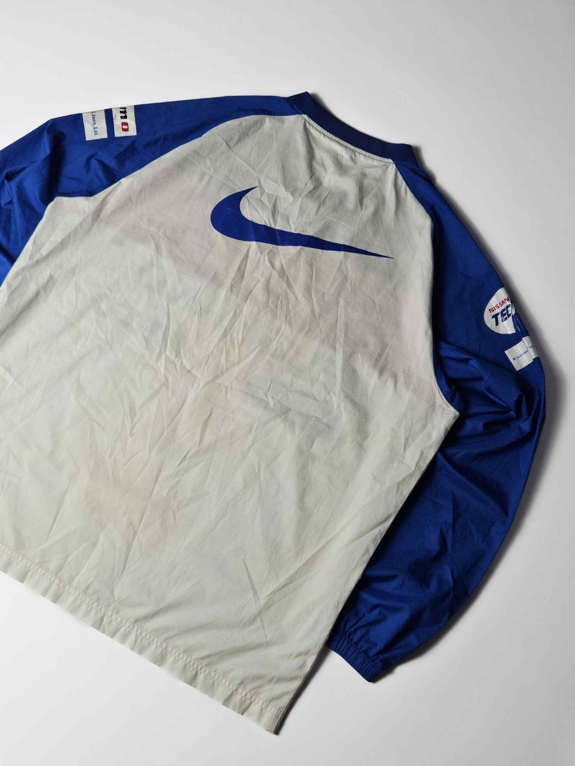 Achterzijde van een authentiek 2000s vintage Yokohama F. Marinos Nike voetbalshirt – grote blauwe Nike swoosh en originele gesponsorde mouwen, populair bij J-League verzamelaars