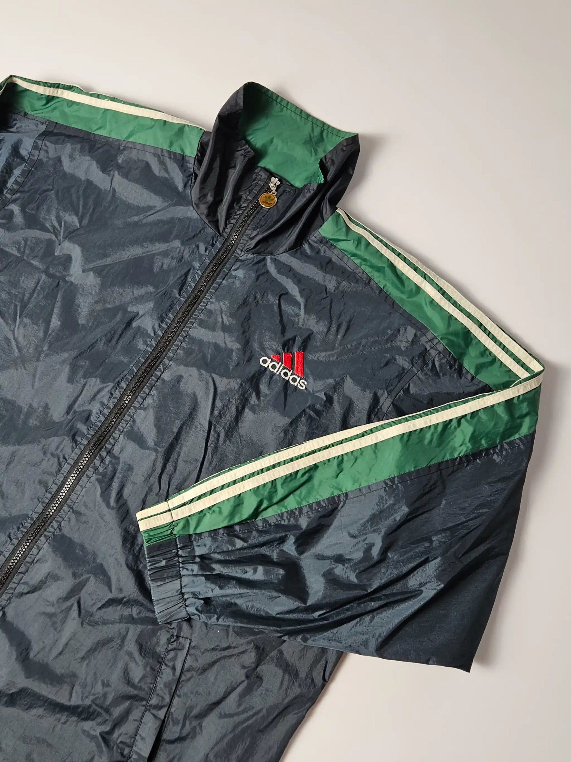 Close-up van geborduurd France 98 World Cup logo en contrasterende Adidas-strepen – iconisch jaren 90 voetbal windbreaker design, populair bij retro streetwear en sportverzamelaars