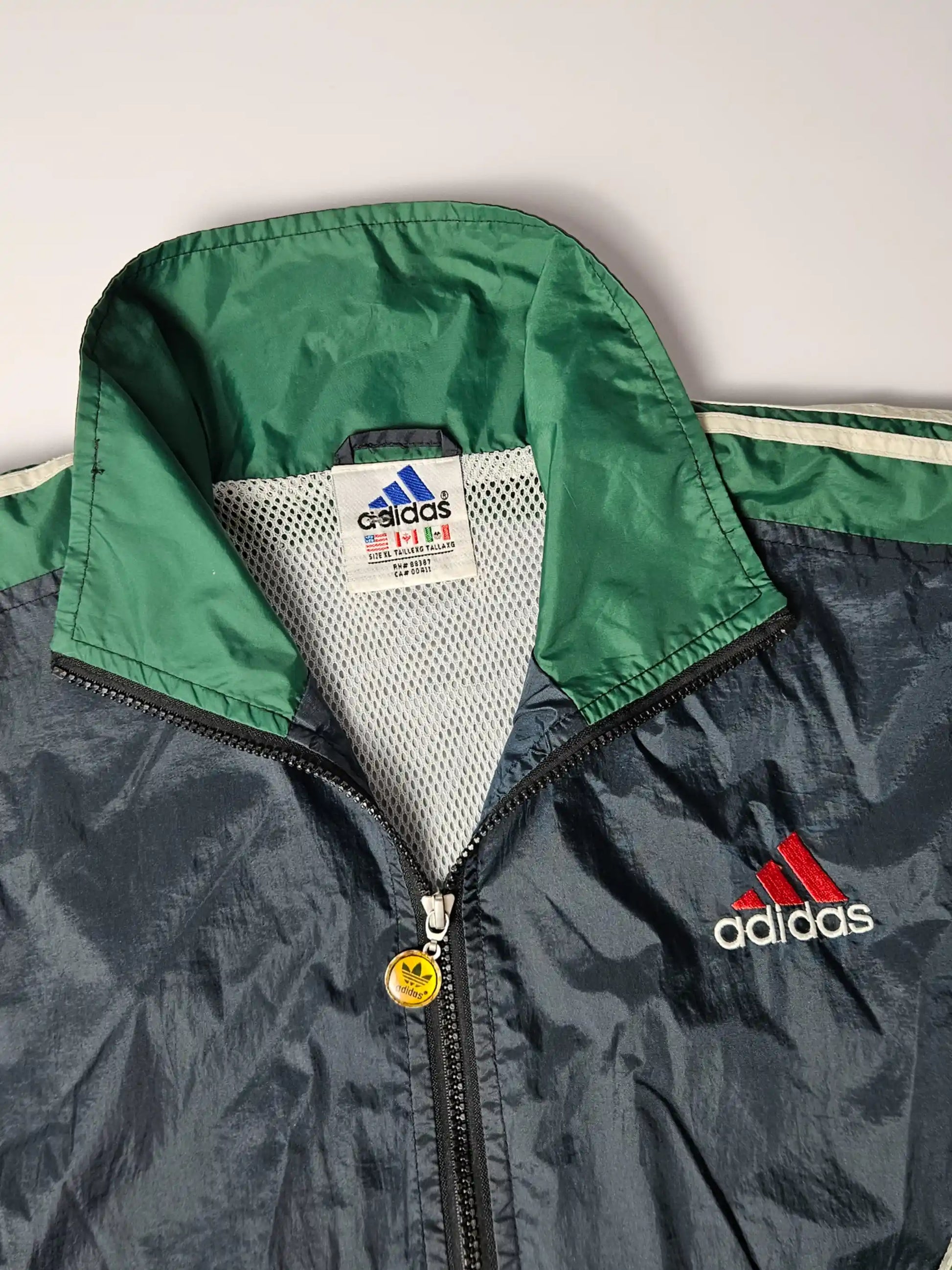 Adidas label – Made in Thailand, typische jaren 90 vintage sportwear met meshvoering en originele rits met geel Adidas-logo, belangrijk authenticatiekenmerk