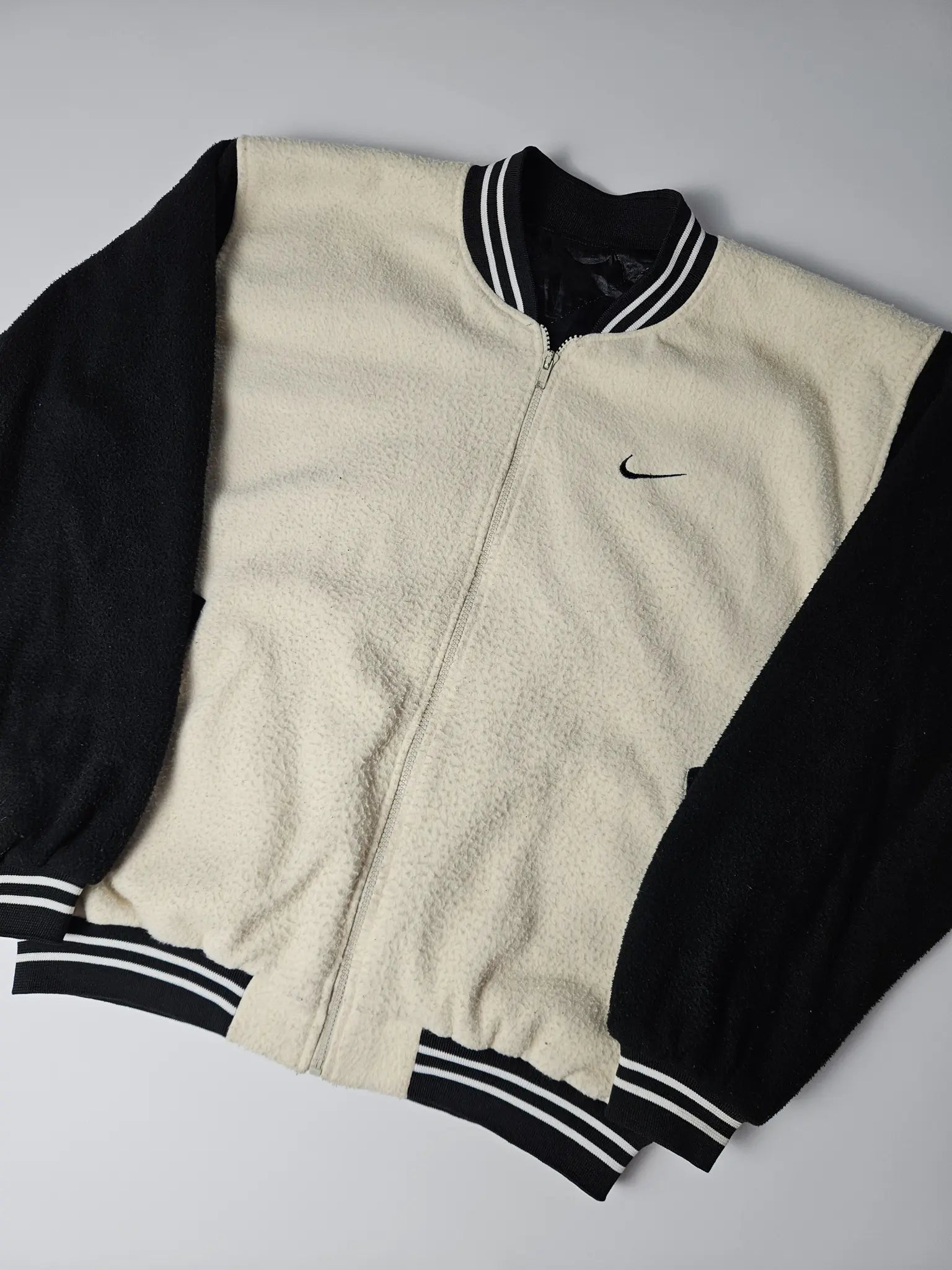 Zwart-beige Nike fleece varsity jacket met geborduurd kleine Nike swoosh op de borst – relaxed fit jaren 90 streetwear en sportstyle collectors item
