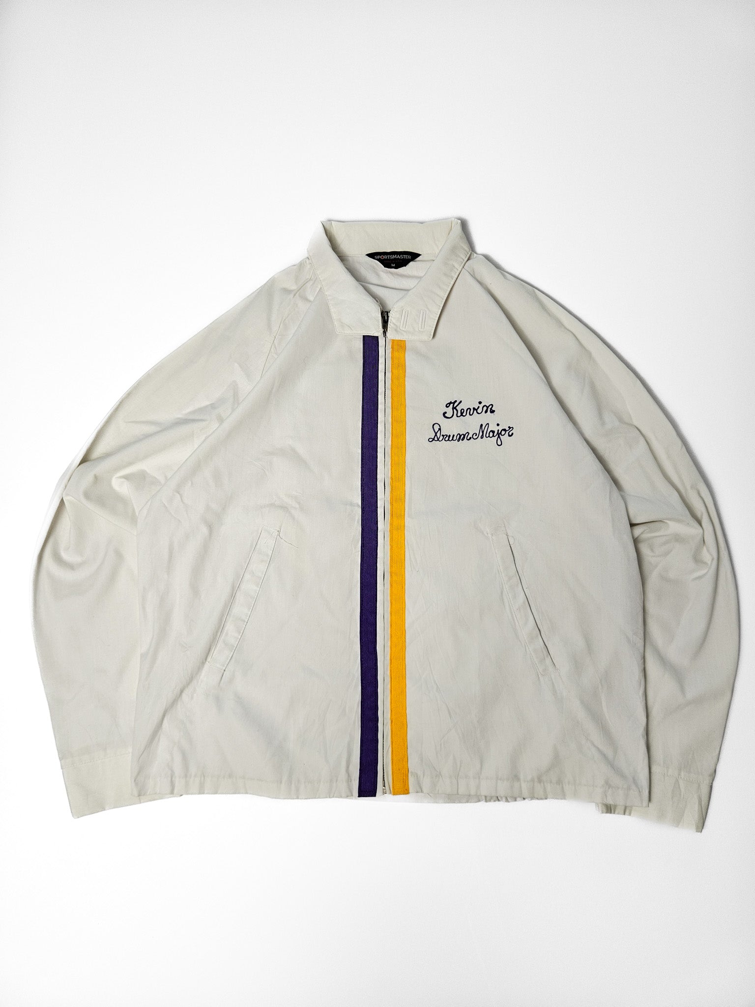 Witte vintage marching band jas met paarse en gele accenten en geborduurde naam “Kevin Drum Major”