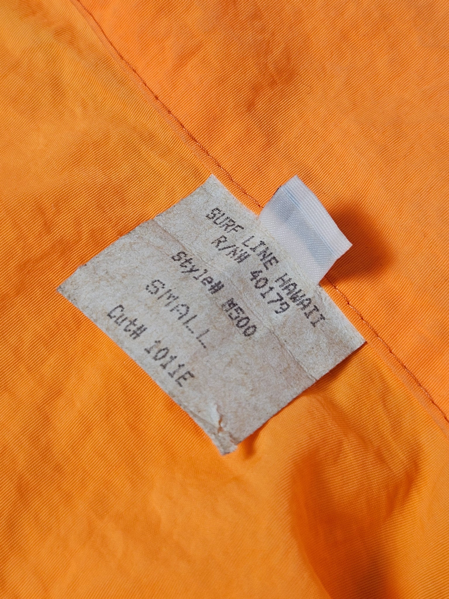 Papieren label met “Surf Line Hawaii” en maat S aan de binnenkant van de jas