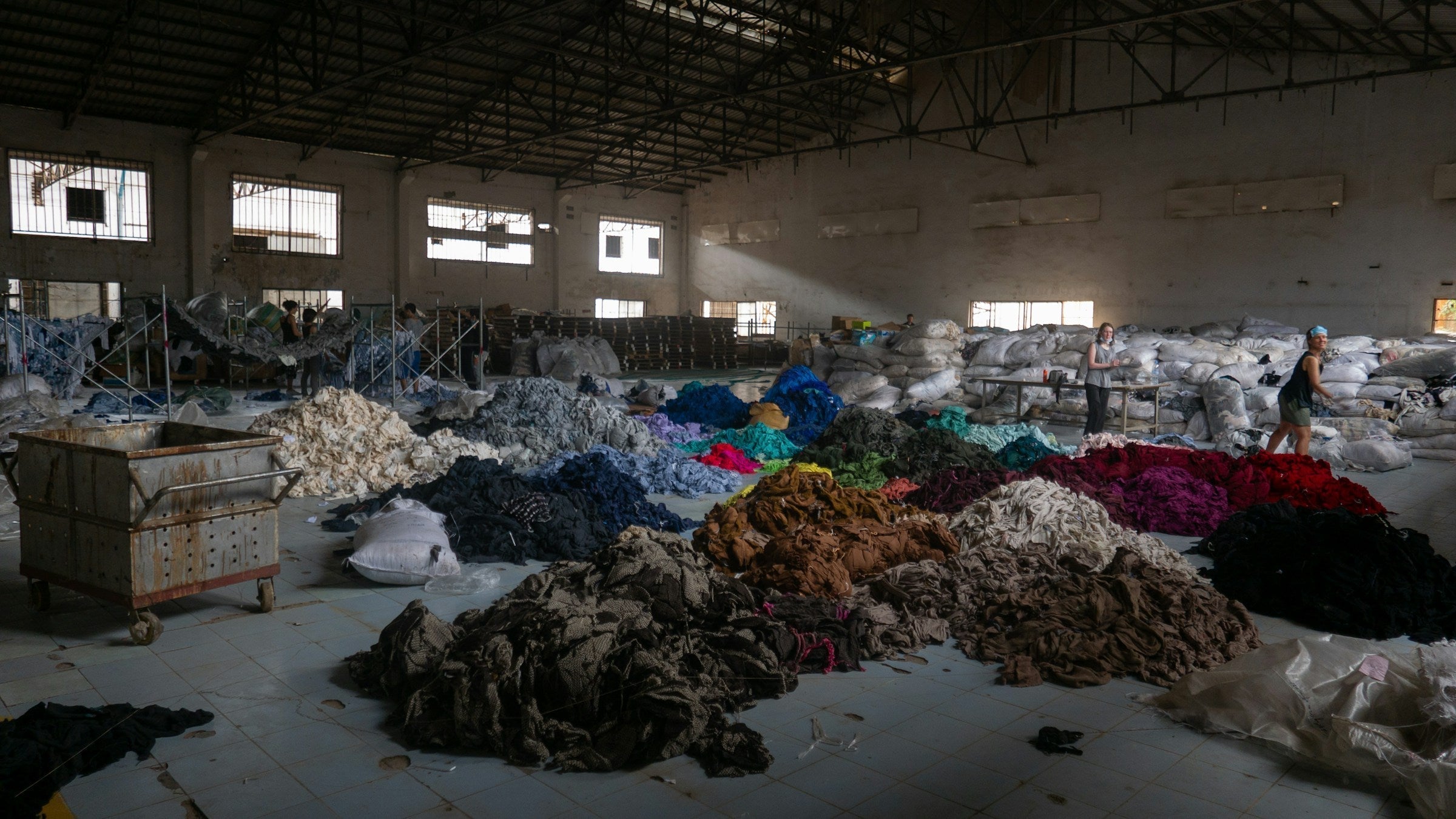 Bergen afgedankte kleding in een loods, symbool voor de vervuiling door fast fashion industrie