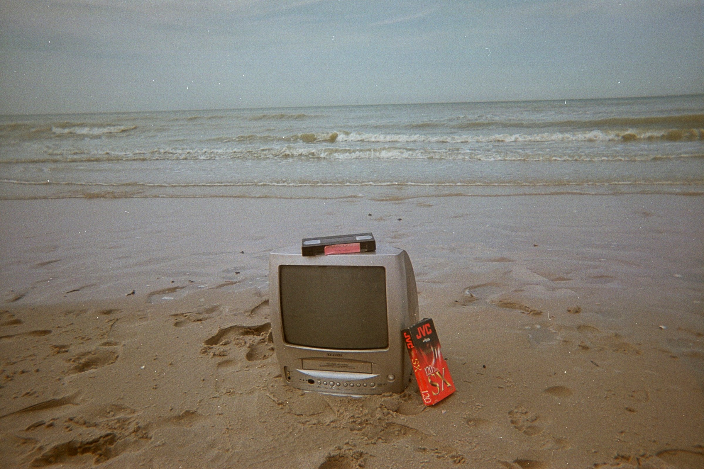 Retro CRT-televisie met VHS-band op een leeg strand – jaren ’90 esthetiek met videokunstgevoel en analoge nostalgie