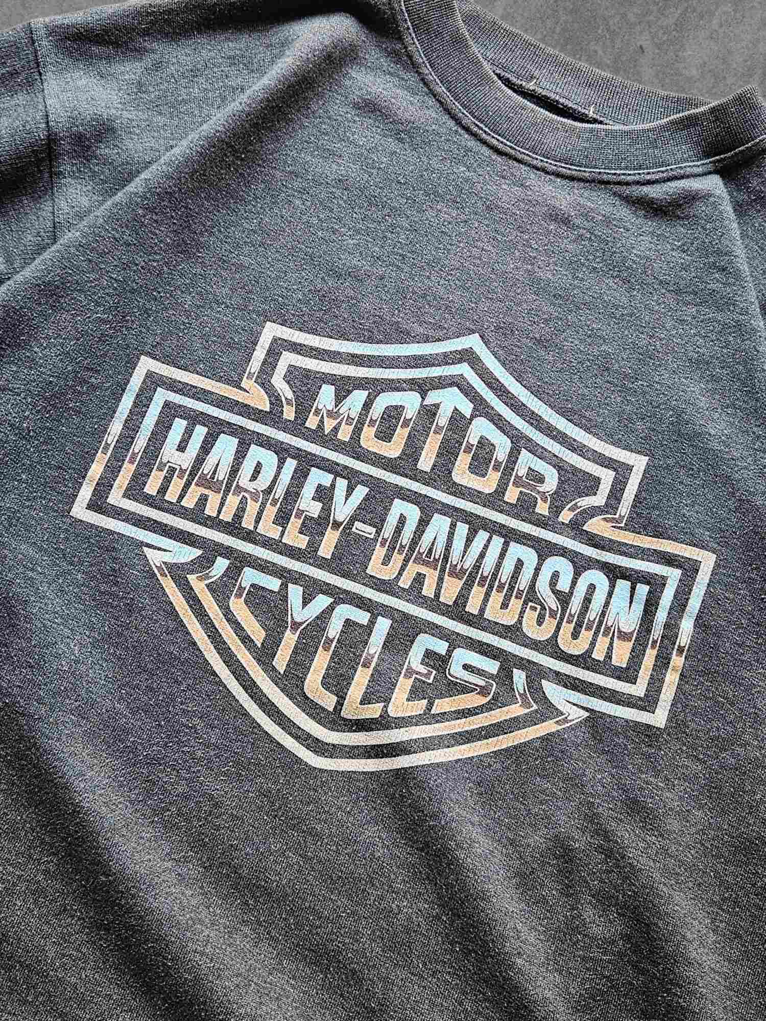Close-up van een donkergrijze vintage Harley-Davidson sweater met vervaagd logo in wit en oranje tinten – klassieke motorstijl met gedragen uitstraling.