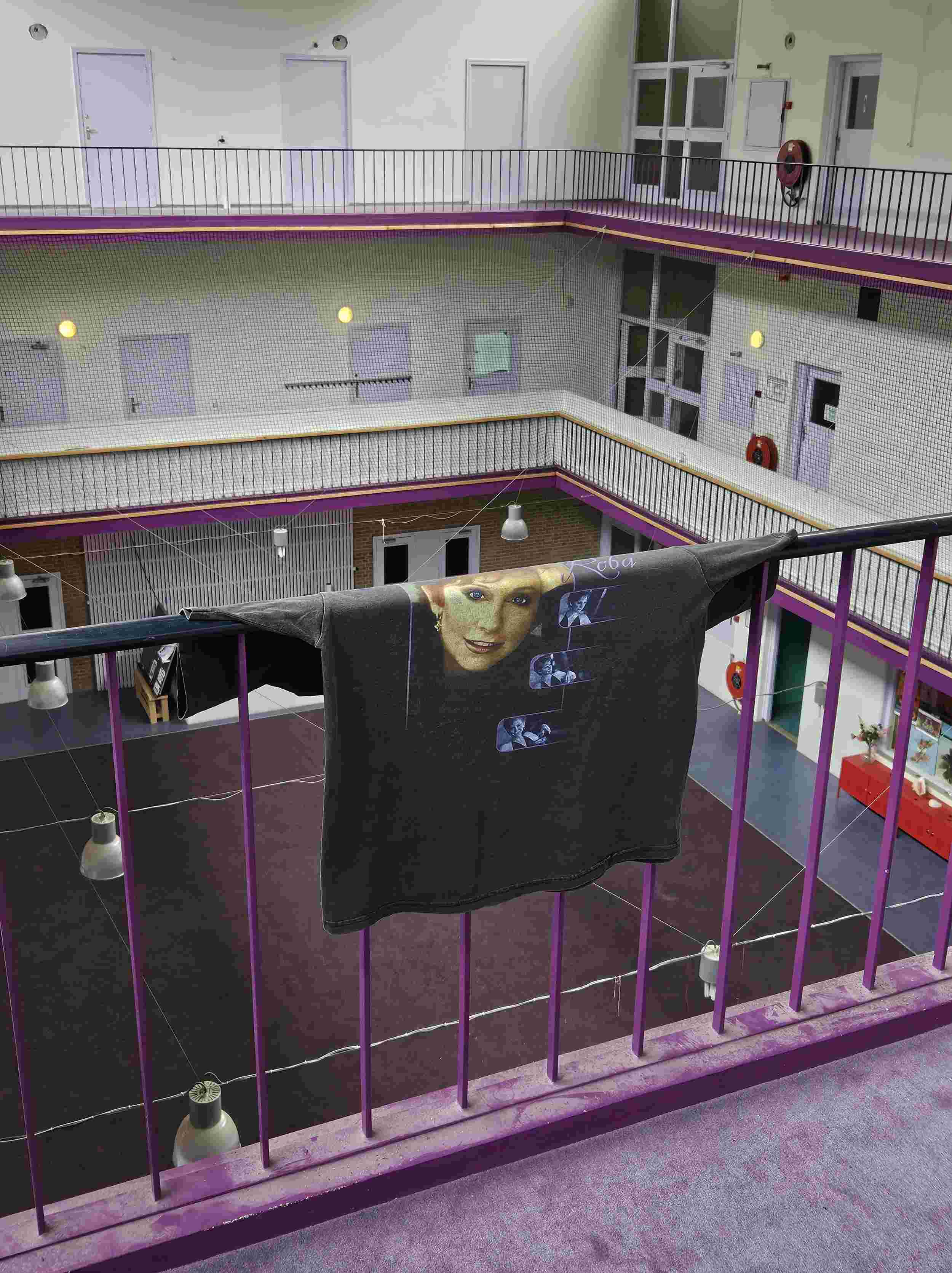 Vintage zwart bandshirt met Reba McEntire print, gedrapeerd over een paarse balustrade in een stedelijke setting – gefotografeerd als onderdeel van de muziekcollectie van Slow Fashion Vintage.
