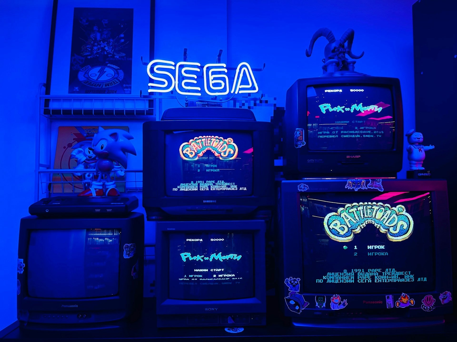 Retro gameroom met stapel CRT-televisies, SEGA neonlicht, Battletoads game en Sonic-figuren in blauwe Y2K-verlichting