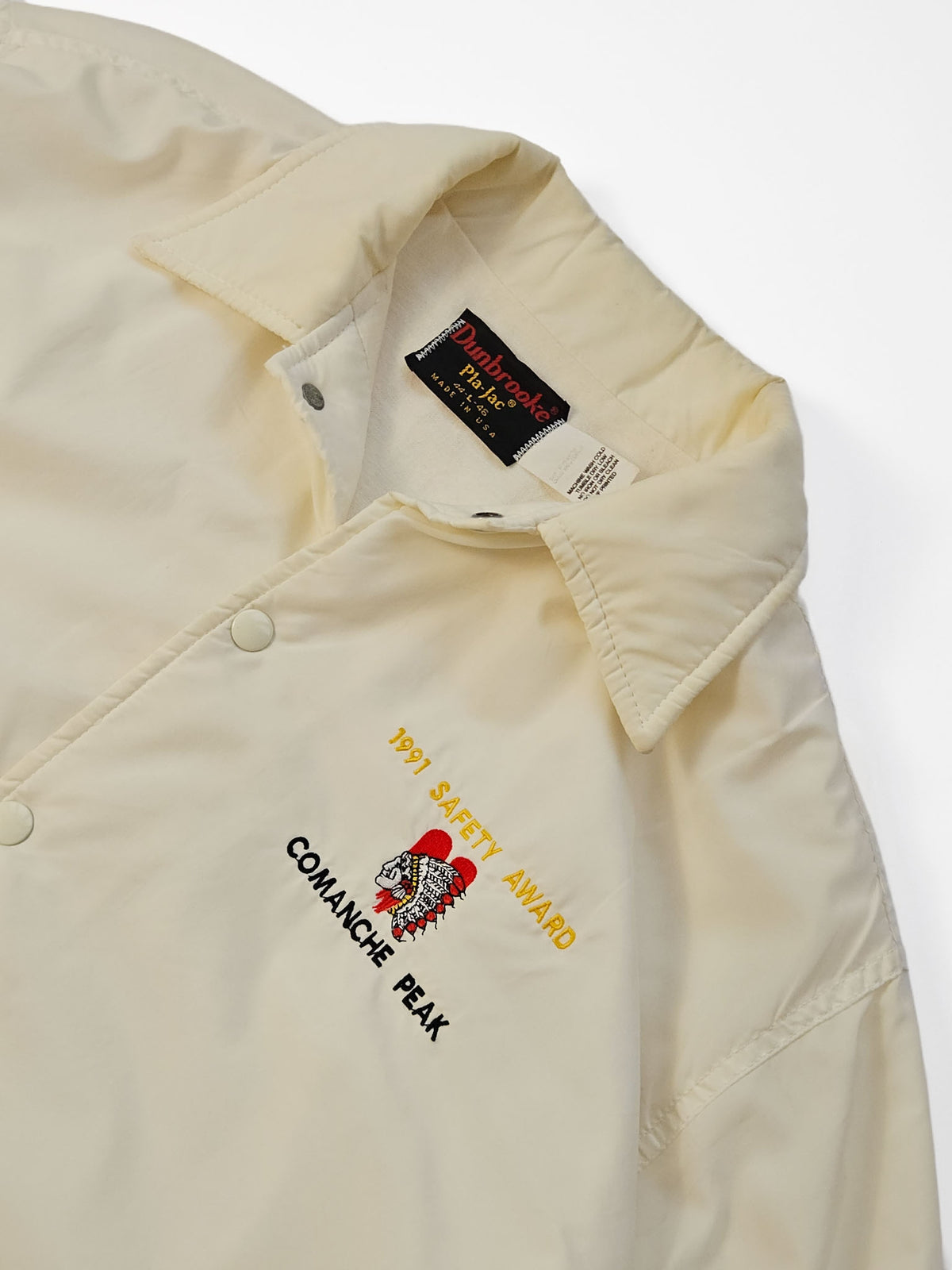 Detail van de puntkraag en het borstborduursel met de tekst ‘1991 Safety Award’ en ‘Comanche Peak’ op het crème coachjack.