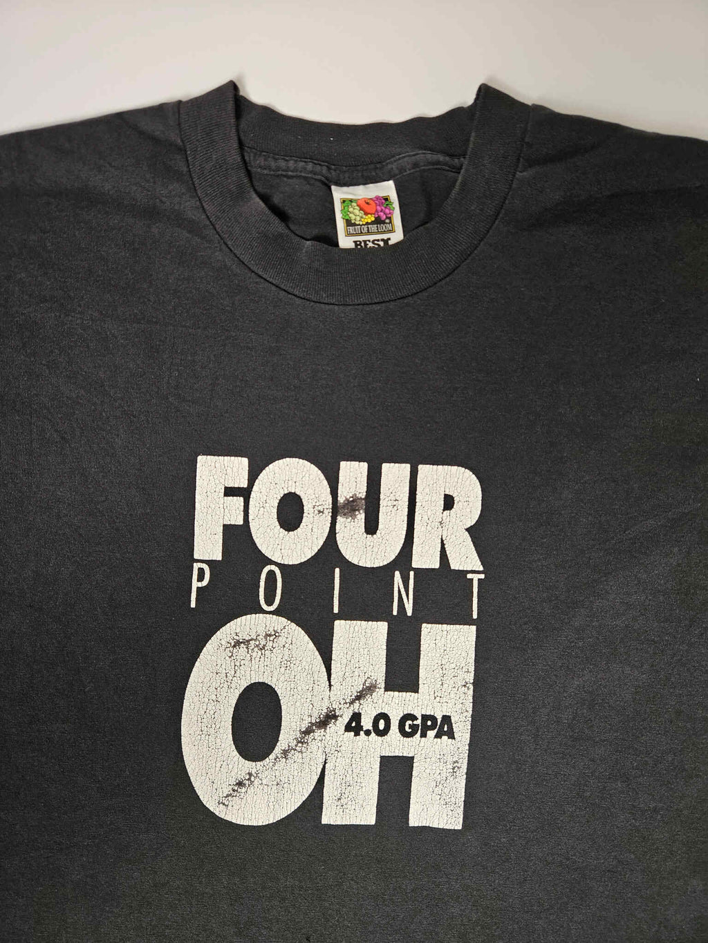 "Voorkant van een zwart vintage T-shirt met een opvallende witte distressed print 'FOUR POINT OH 4.0 GPA'. De tekst heeft een verweerde look die bijdraagt aan de vintage uitstraling. Een perfect voorbeeld van een uniek, pre-loved item binnen de slow fashion collectie."

