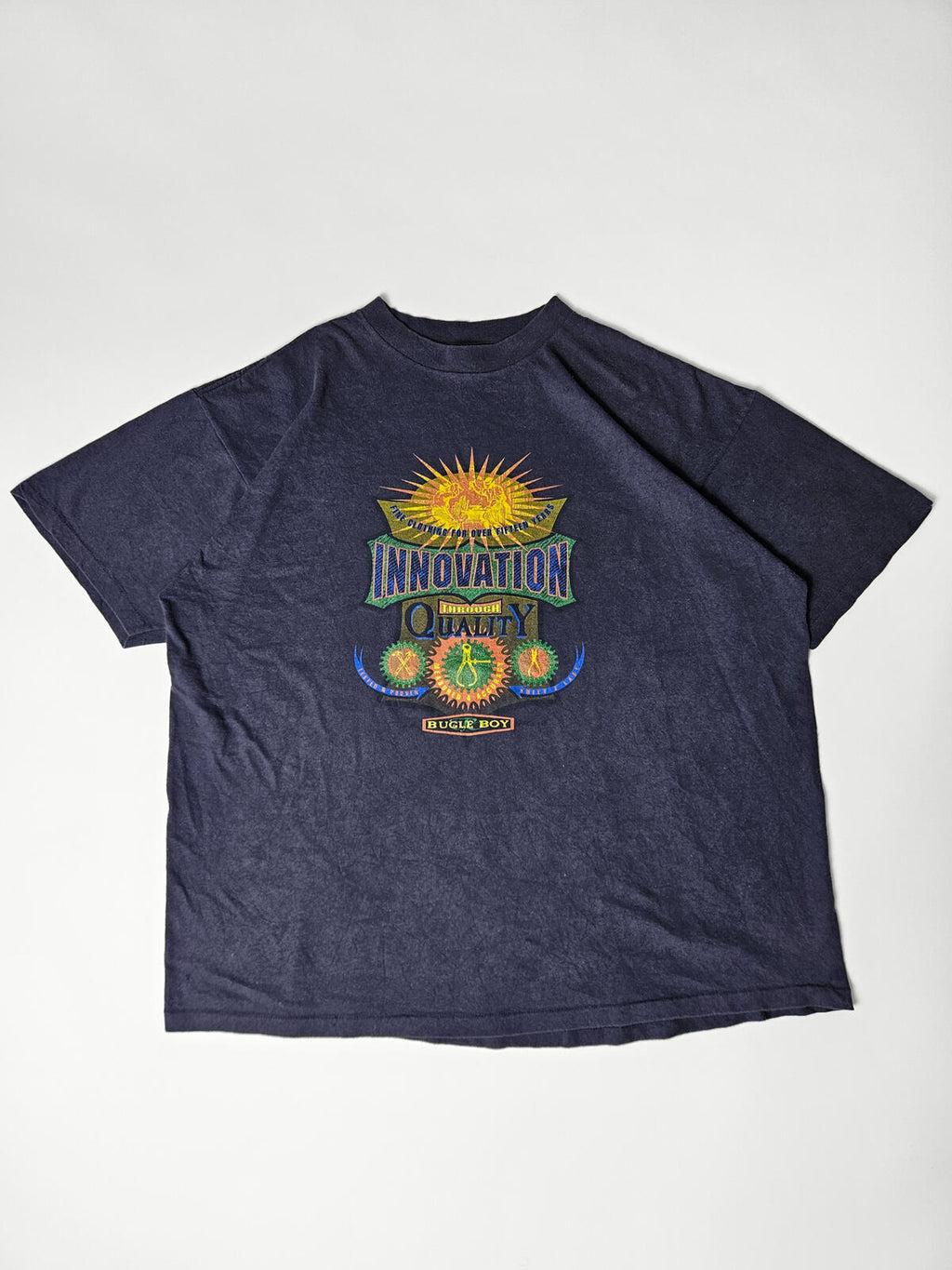Flatlay van authentiek Bugle Boy 'Innovation Through Quality' promo T-shirt uit de jaren 90 – zeldzaam item voor retro workwear en streetwear liefhebbers