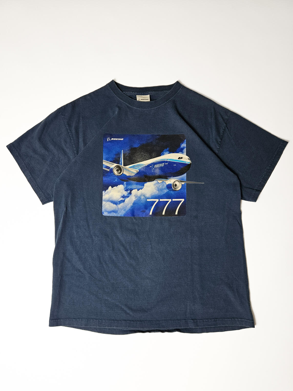 Flatlay van authentiek Boeing 777 promo T-shirt uit de jaren 90 met retro luchtvaartdesign – uniek verzamelstuk voor airline crew en aviation fashion liefhebbers