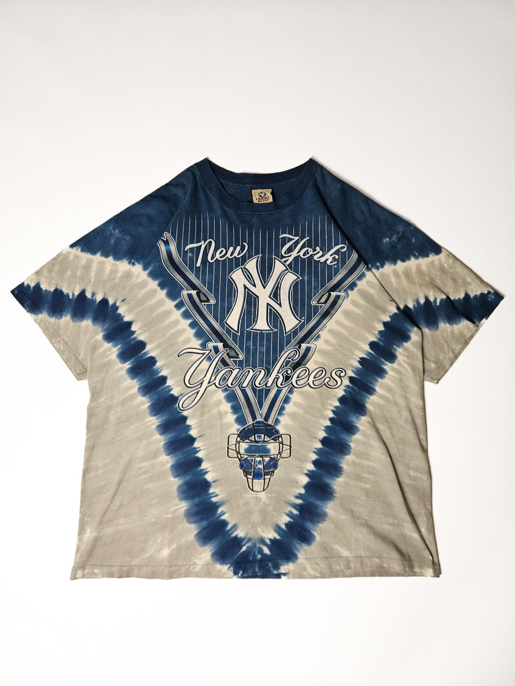 "Vintage New York Yankees tie-dye T-shirt met iconisch pinstripe logo en catcher-masker print – jaren 90 stijl, populair onder MLB fans en vintage streetwear verzamelaars"

