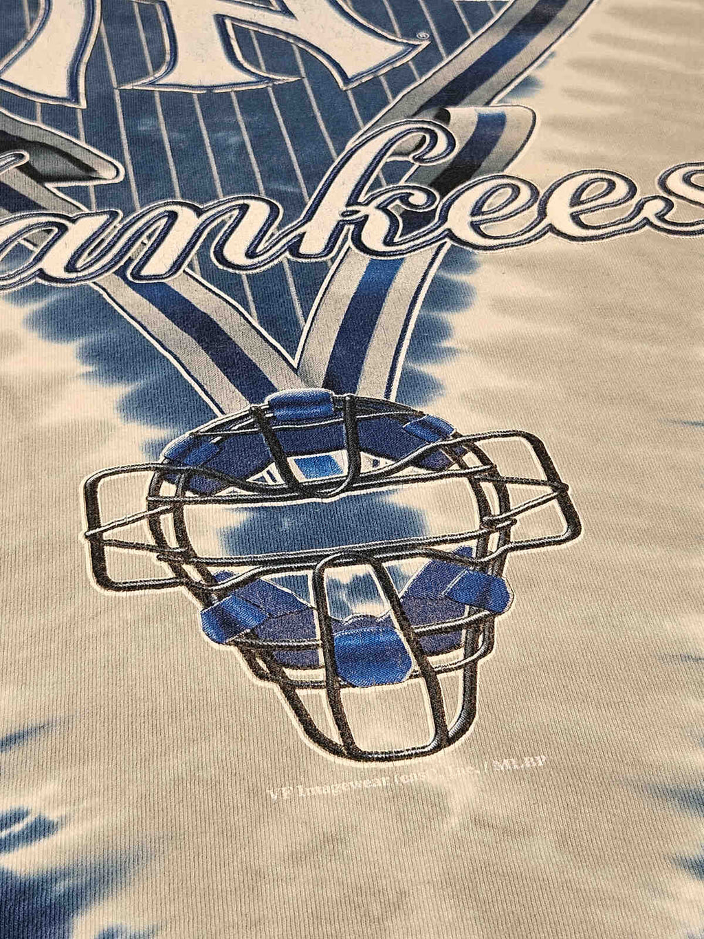 "Close-up van Yankees plastisol-print met subtiele vintage craquelé en tie-dye patroon – typisch jaren 90 MLB merchandise, geliefd bij verzamelaars"

