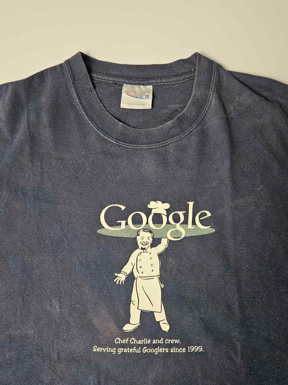 "Close-up van Google Chef Charlie grafische print op vintage Hanes T-shirt – subtiele veroudering en originele plastisol-inkt, typisch Y2K corporate merchandise"

