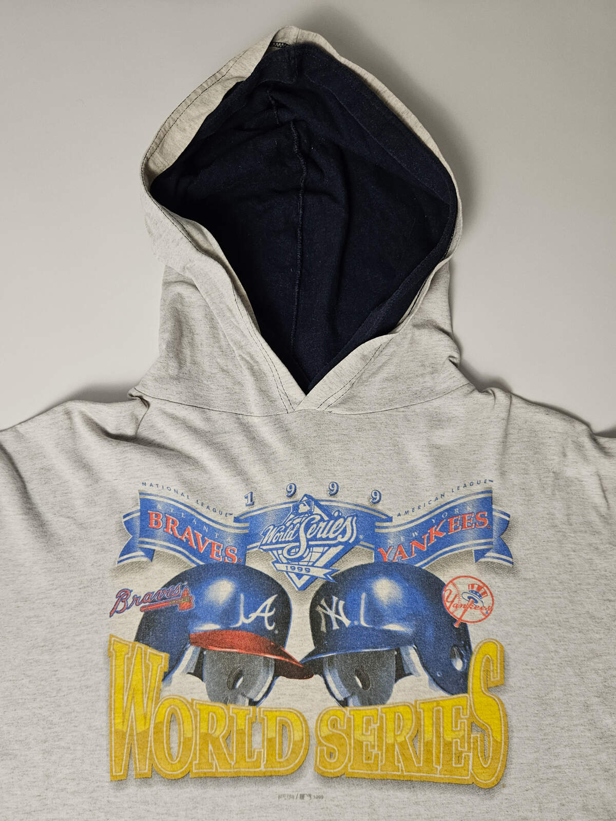 "Vintage 1999 World Series hoodie T-shirt met Braves en Yankees helmen – authentieke MLB merch, populair bij baseball en sport heritage verzamelaars"


