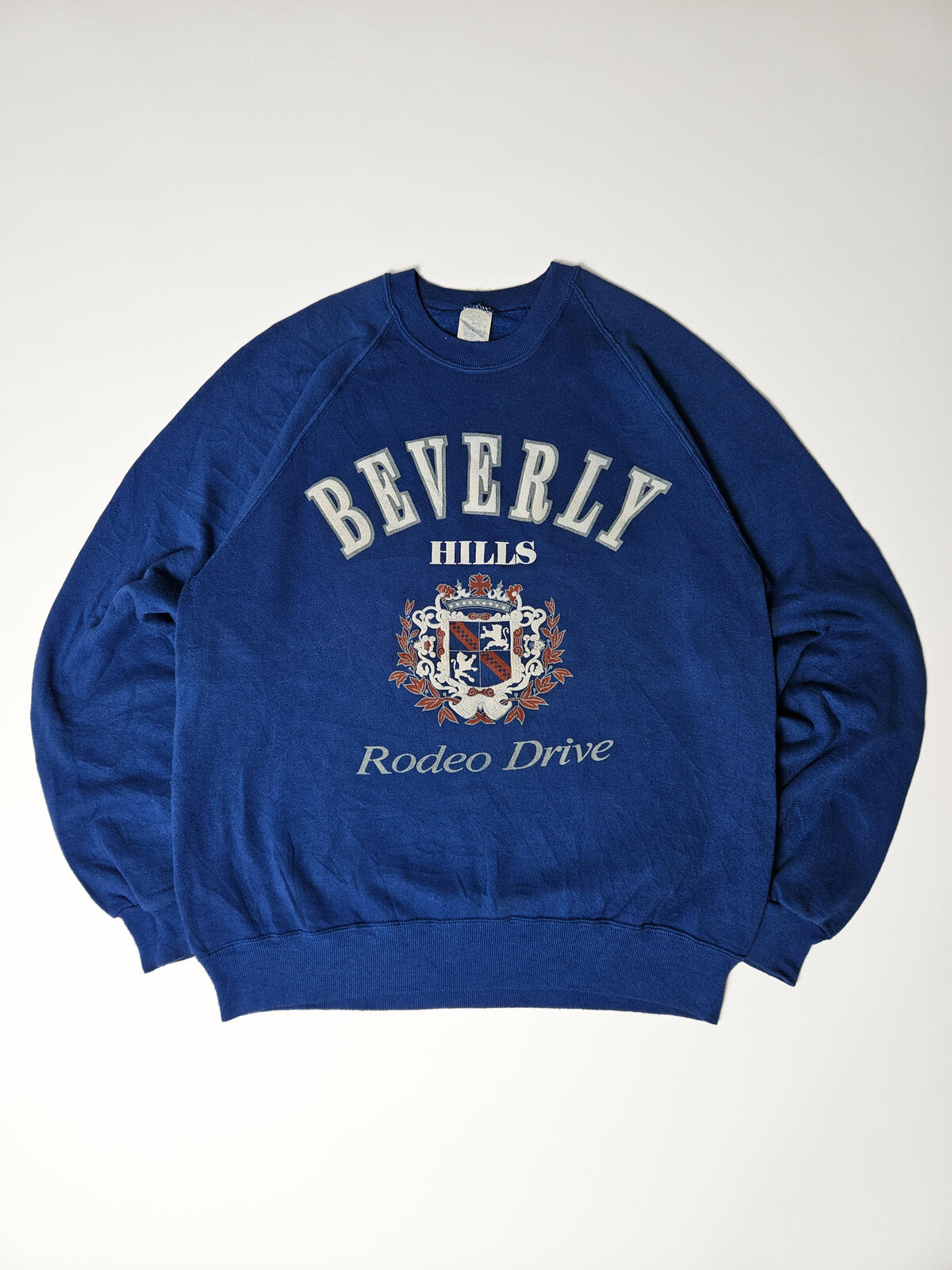 "Vintage Beverly Hills Rodeo Drive sweater in koningsblauw met groot crest logo – klassieke preppy Amerikaanse stijl, populair bij 90s streetwear en resortwear liefhebbers"

