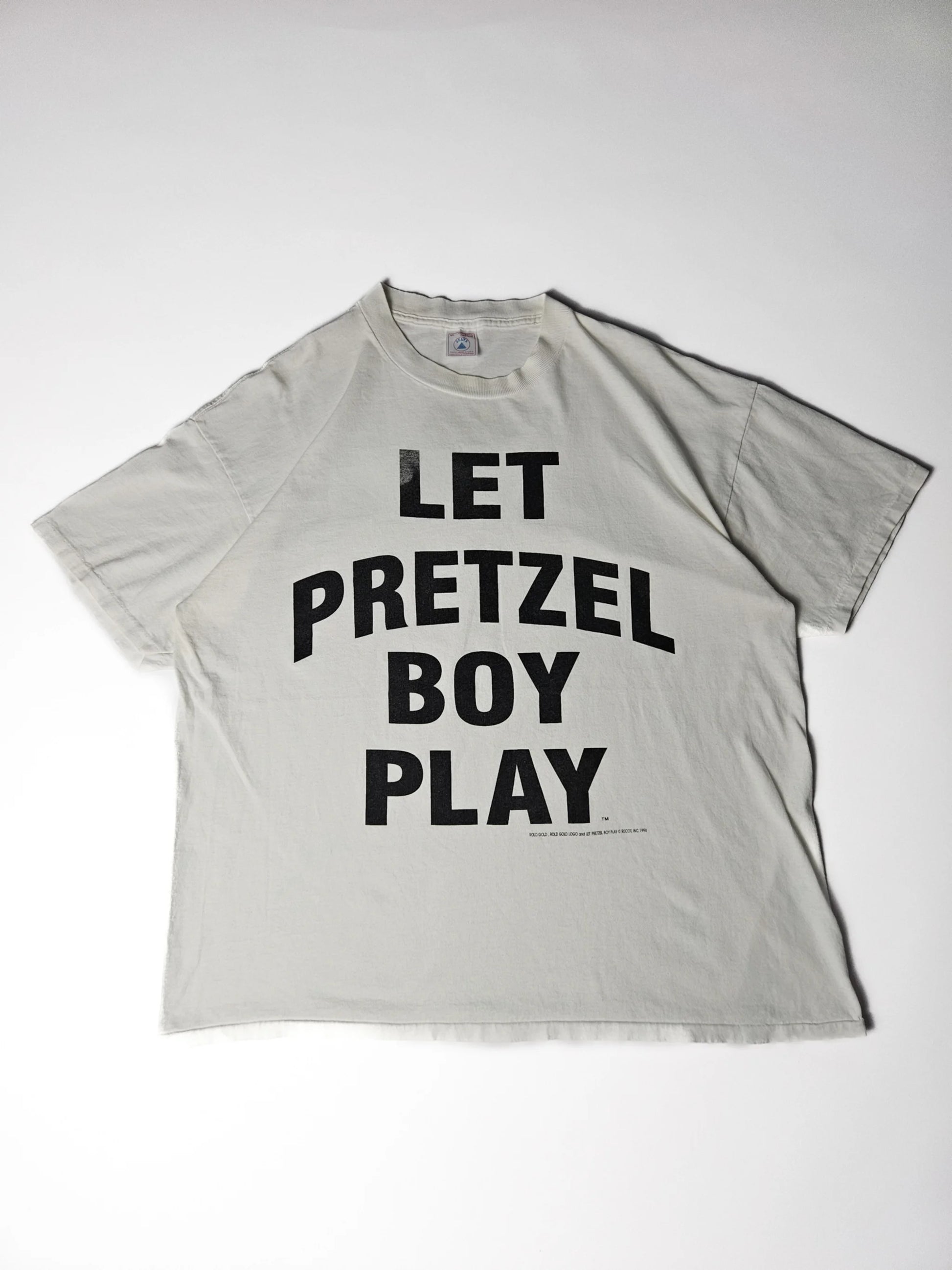 Authentiek 1996 vintage Delta Let Pretzel Boy Play T-shirt in wit met grote zwarte typografische print – single stitch Made in USA, geliefd bij streetwear en reclame T-shirt verzamelaars

