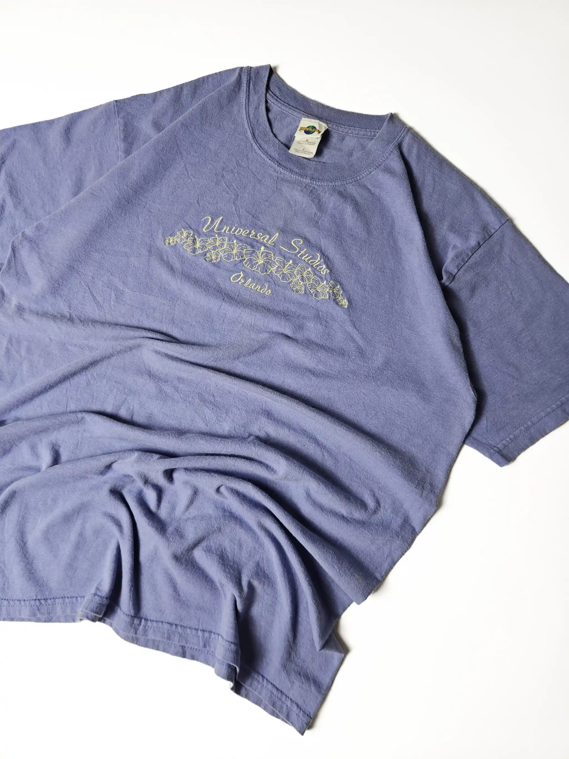 Authentiek jaren 90 vintage Universal Studios Orlando T-shirt in paars katoen – geborduurde hibiscus bloemen en Orlando script, populair bij theme park en retro vakantie T-shirt verzamelaars

