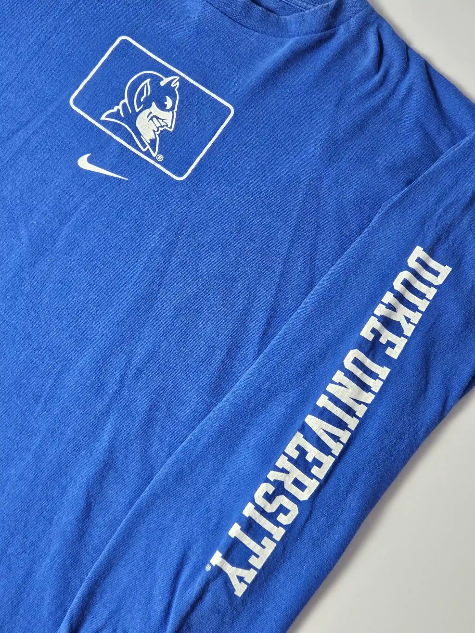 Witte Duke University sleeve print op blauw katoen – iconisch college sports design uit de jaren 90, geliefd bij American collegewear fans en sportverzamelaars

