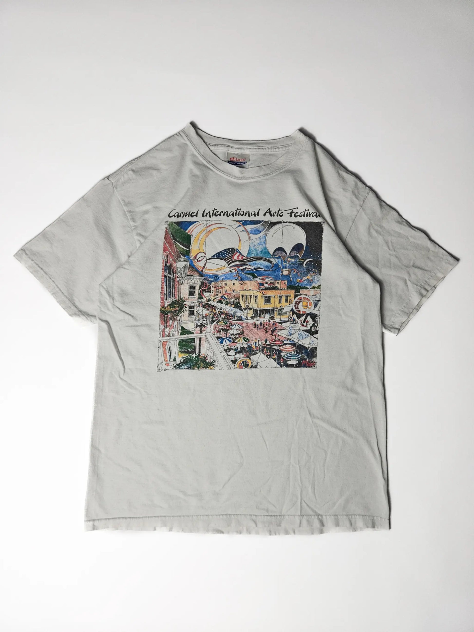 Origineel jaren 90 Hanes Heavyweight Carmel International Arts Festival T-shirt in wit – kleurrijke illustratie van festival met luchtballonnen en druk stadsplein, geliefd bij kunst- en festival T-shirt verzamelaars

