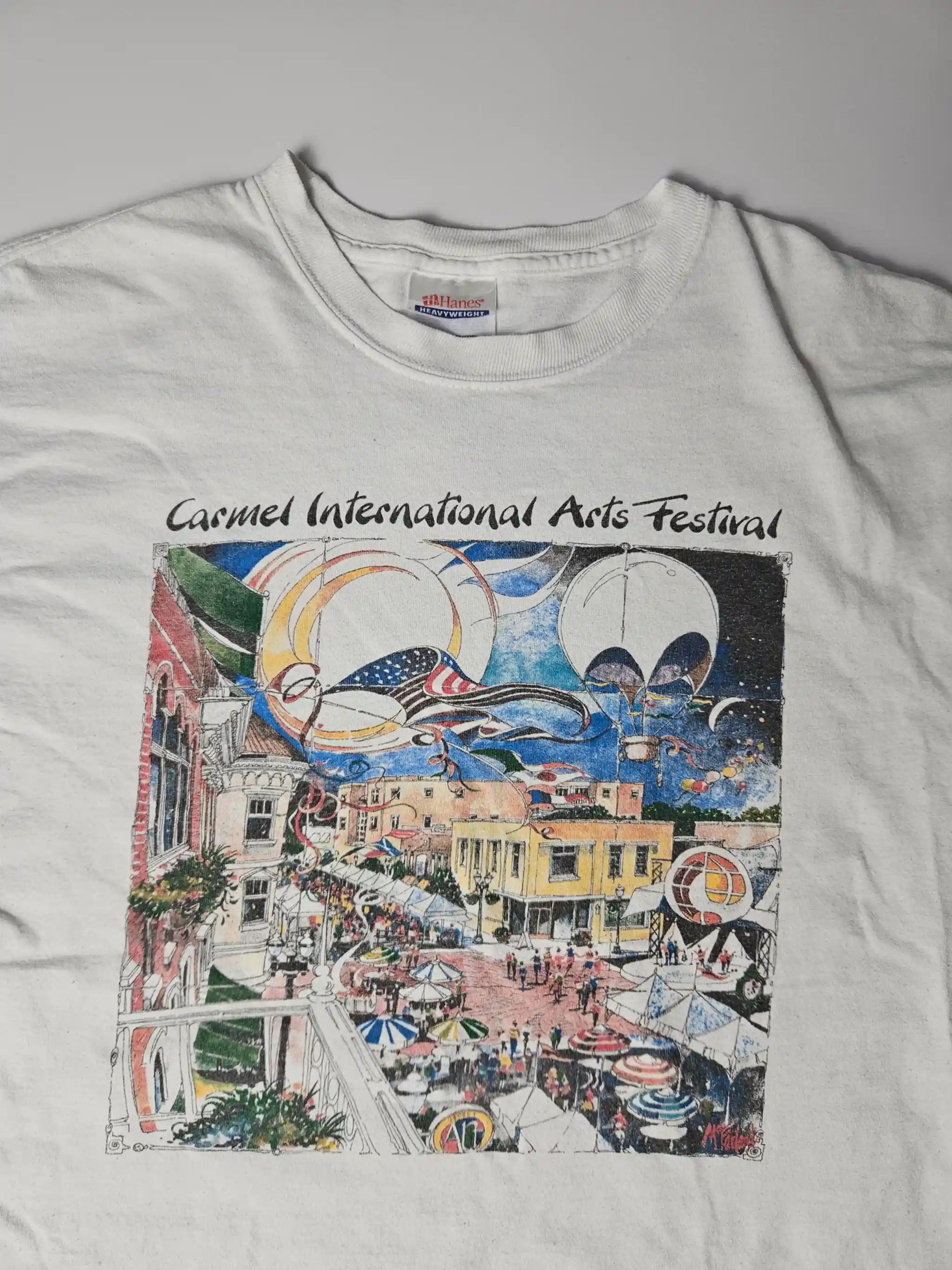 Origineel jaren 90 Hanes Heavyweight Carmel International Arts Festival T-shirt in wit – kleurrijke illustratie van festival met luchtballonnen en druk stadsplein, geliefd bij kunst- en festival T-shirt verzamelaars

