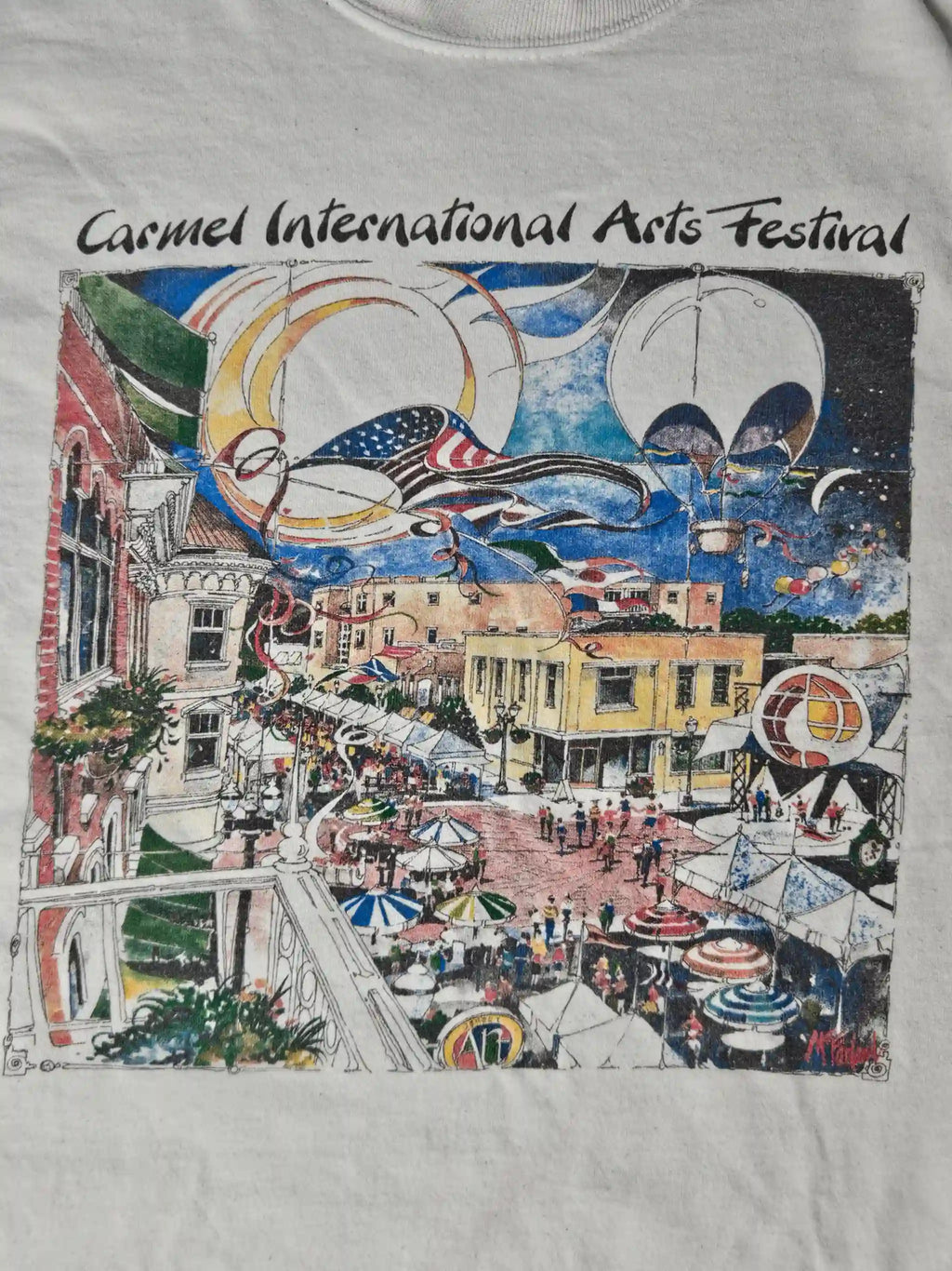 Close-up van Carmel International Arts Festival print – kleurrijke illustratie met luchtballonnen, vlaggen en mensen op een bruisend plein, typisch 90s event merchandise stijl

