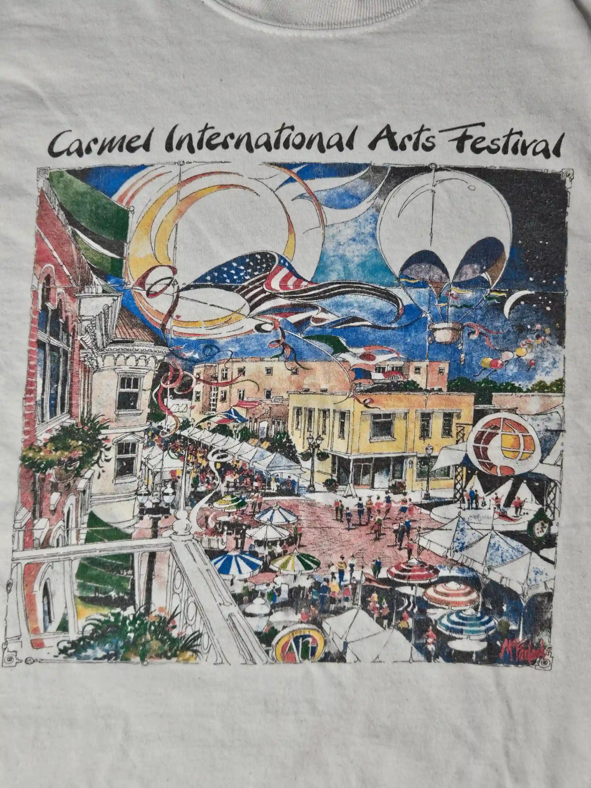 Close-up van Carmel International Arts Festival print – kleurrijke illustratie met luchtballonnen, vlaggen en mensen op een bruisend plein, typisch 90s event merchandise stijl

