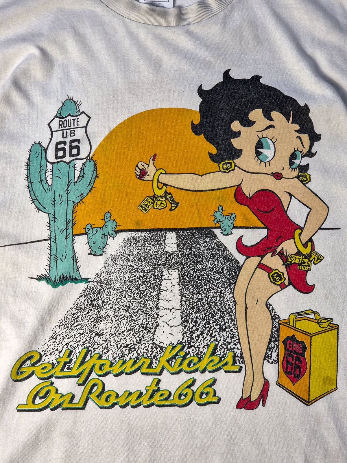 Detail van een ecru Betty Boop vintage T-shirt uit de jaren '90 met faded Route 66 zeefdruk, kleine vlekjes en zichtbare gebruikssporen.