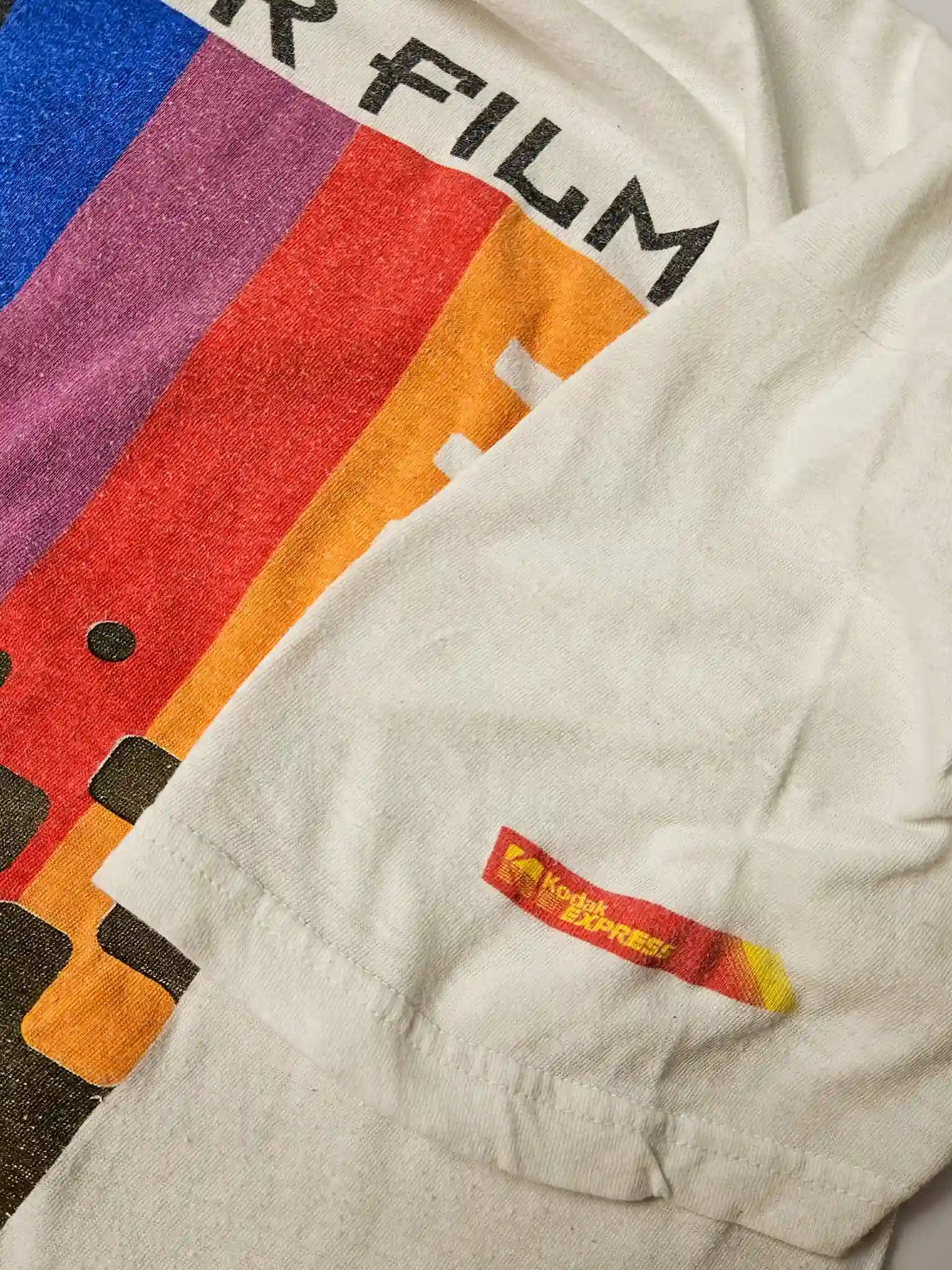 Detail: Close-up van regenboogprint en tekst "Is Your Film as Good as Gold"

