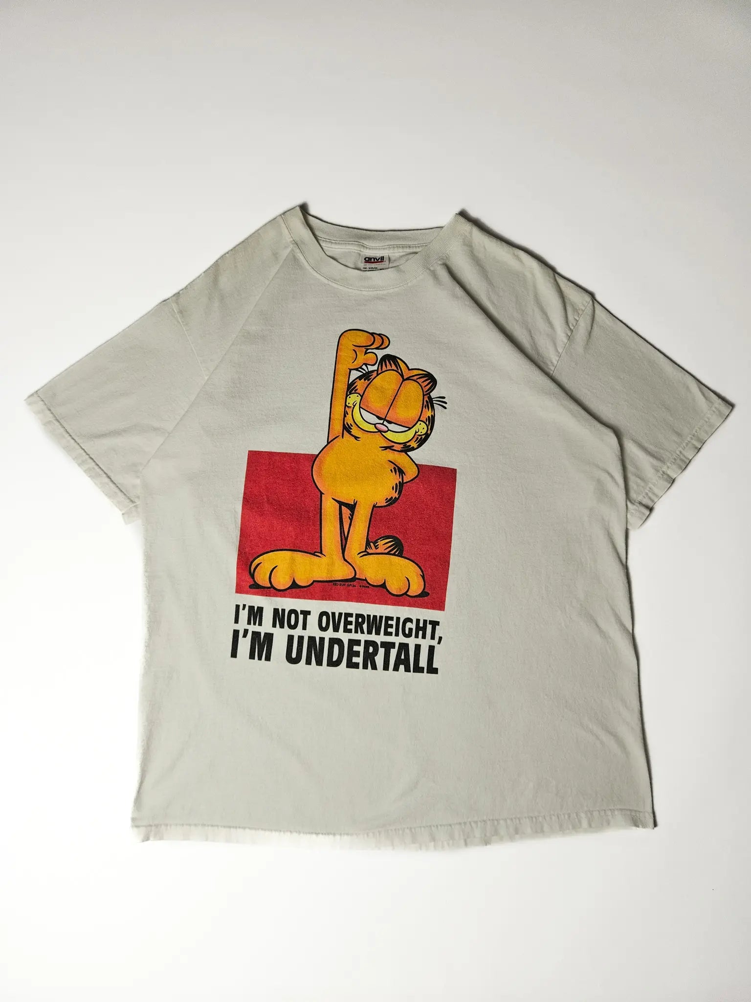 Flatlay: Licht gebroken wit Garfield shirt met kleurrijke frontprint

