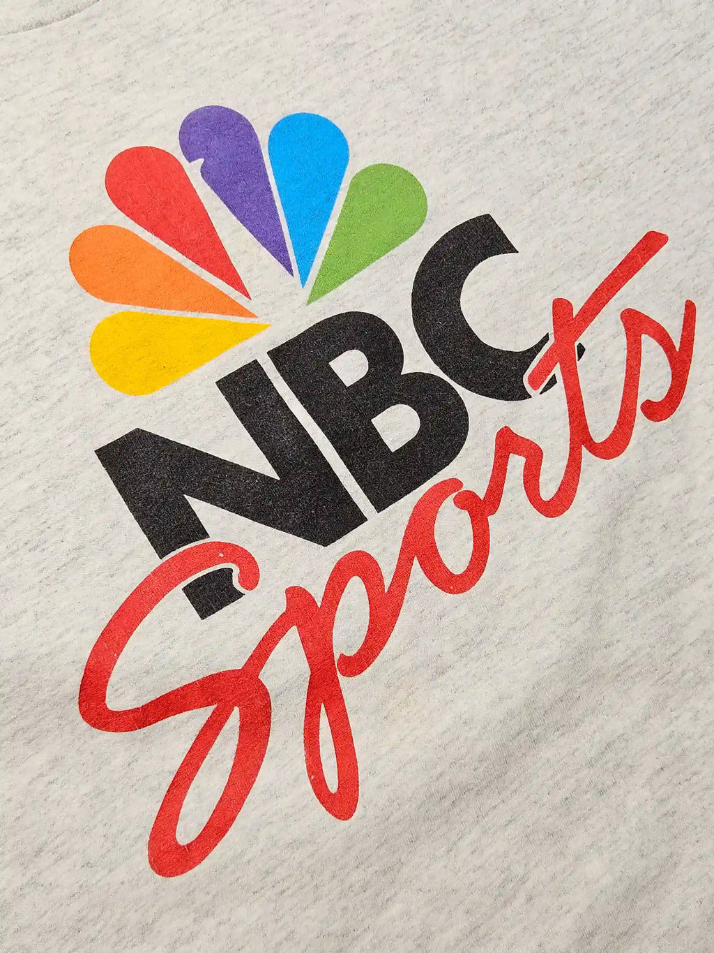 Detail: Close-up van de kleurrijke NBC Sports print op grijs katoen

