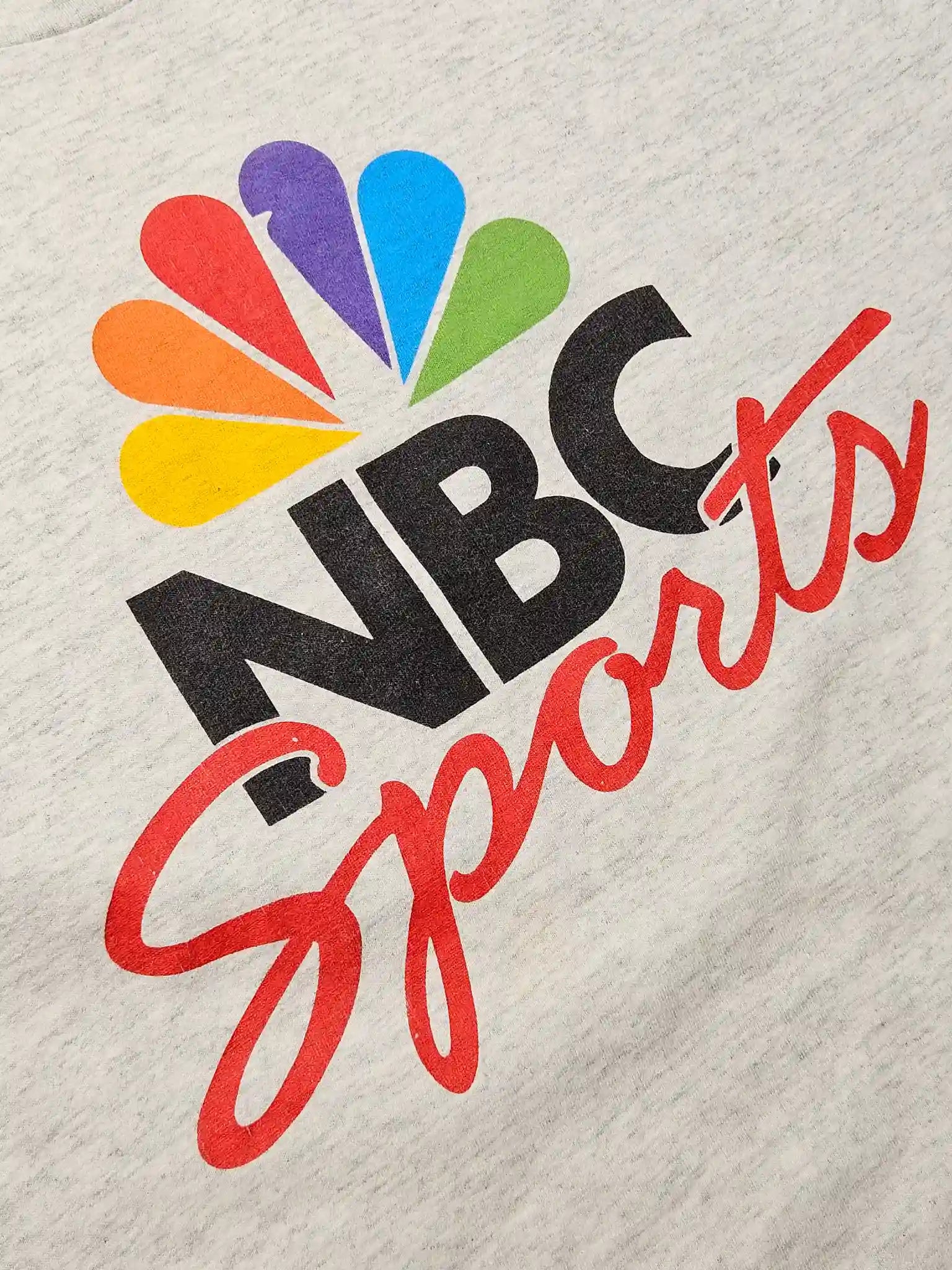 Detail: Close-up van de kleurrijke NBC Sports print op grijs katoen

