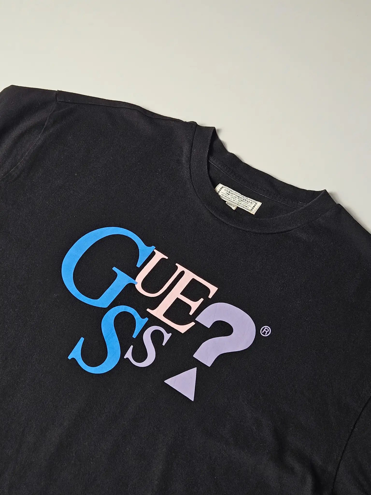 Detail: Close-up van GUESS print in blauw, roze en paars met vraagteken

