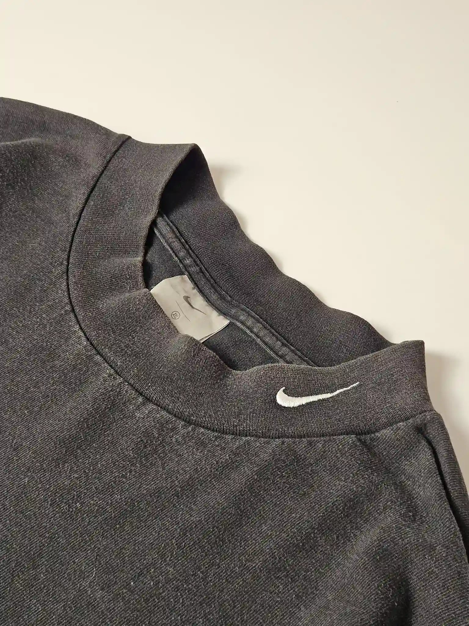 Detail: Close-up van geborduurde witte mini Swoosh op de kraag

