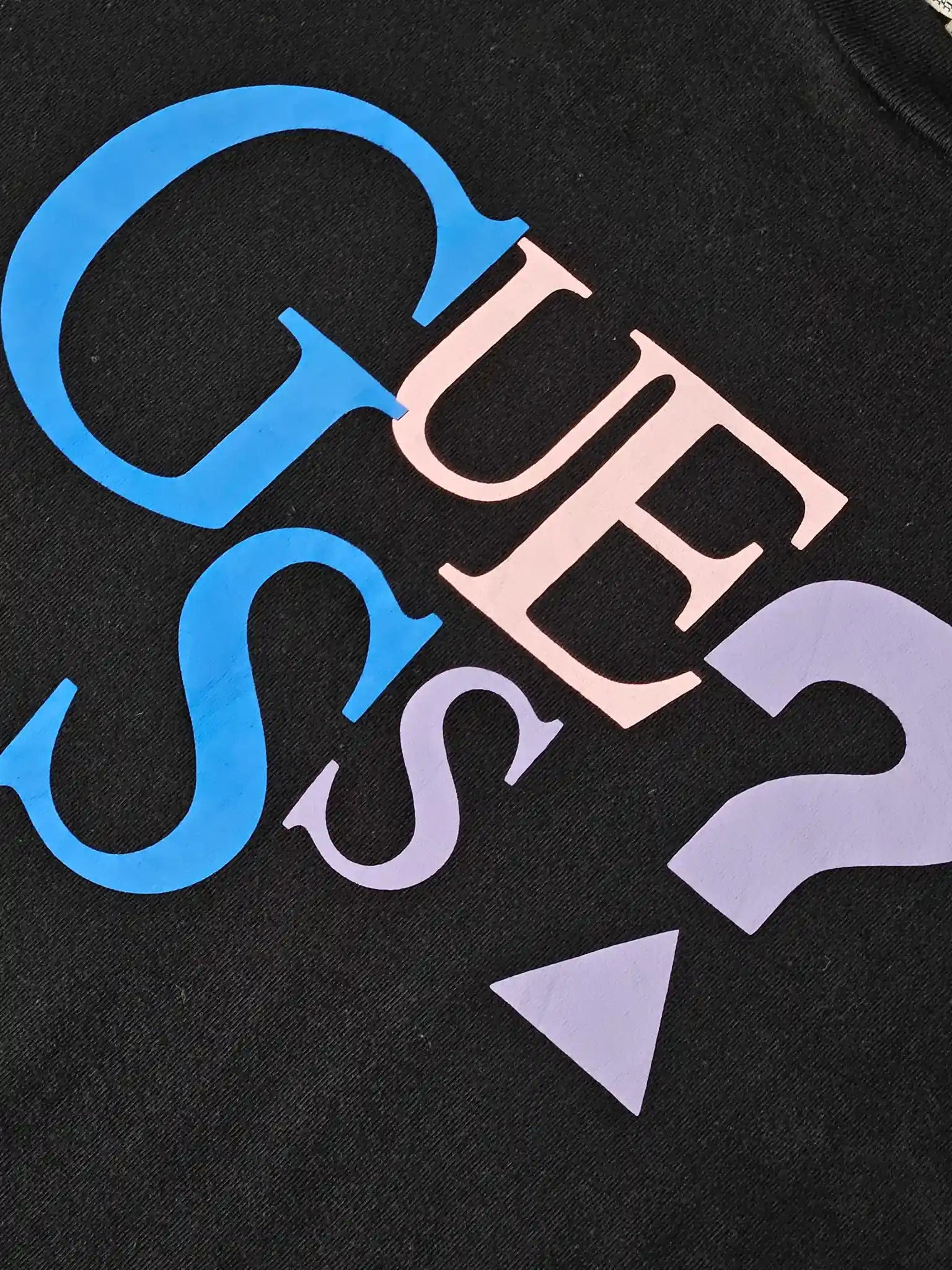 Detail: Close-up van GUESS print in blauw, roze en paars met vraagteken

