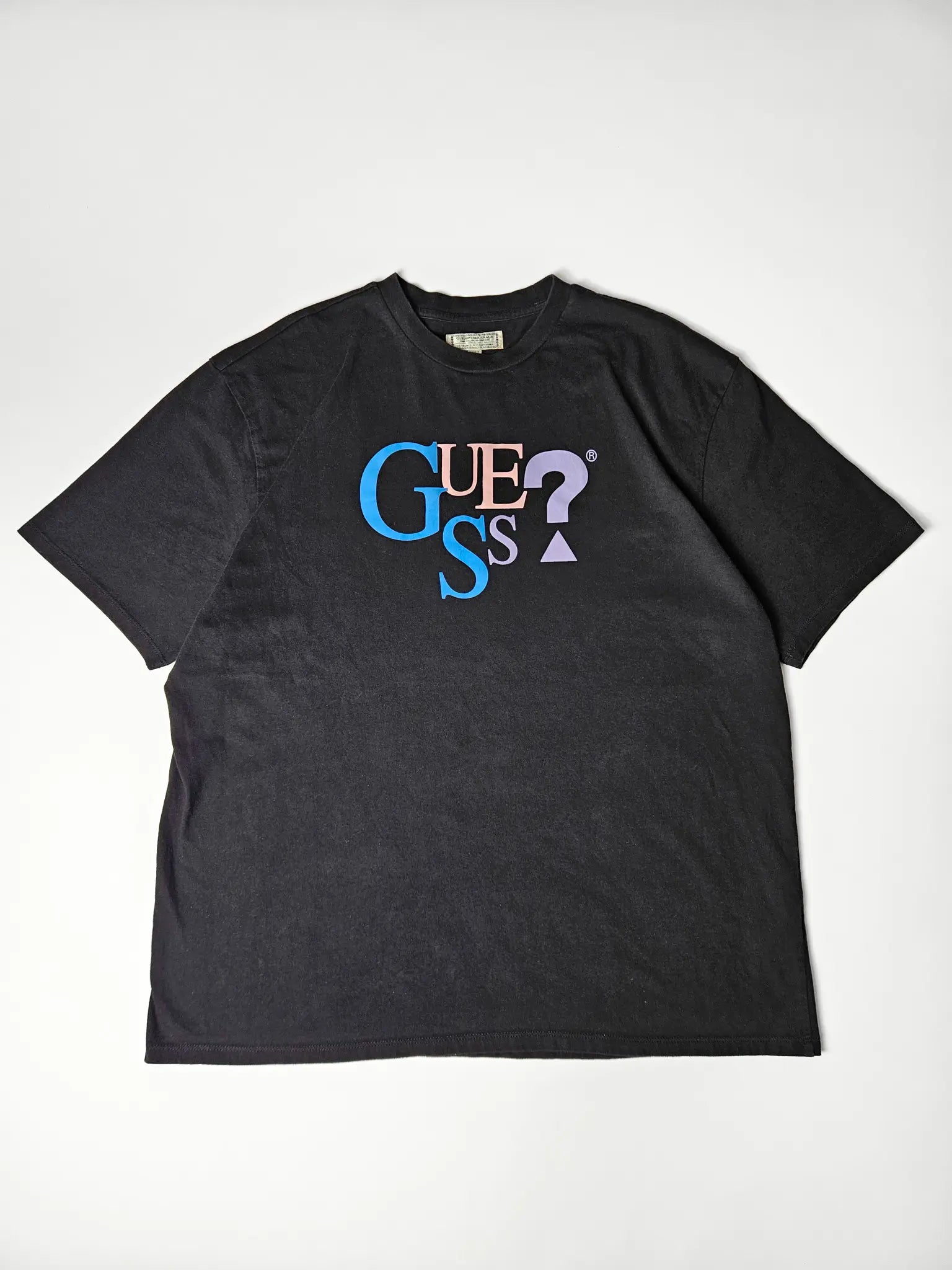 Flatlay: Geheel platgelegd Guess shirt met kleurrijke logoprint

