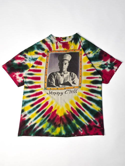 Vintage Jimmy Cliff World Tour T-shirt uit 1995 in multicolor tie-dye met grote front- en backprint, liggend gefotografeerd.
