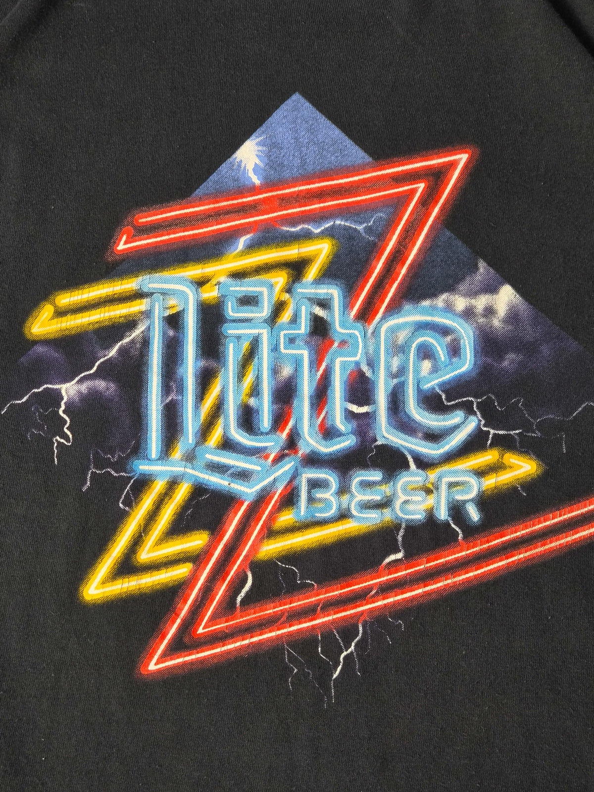 Close-up van de Lite Beer-print met rode en gele Z’s, blauwe neonletters en fijne craquelure.