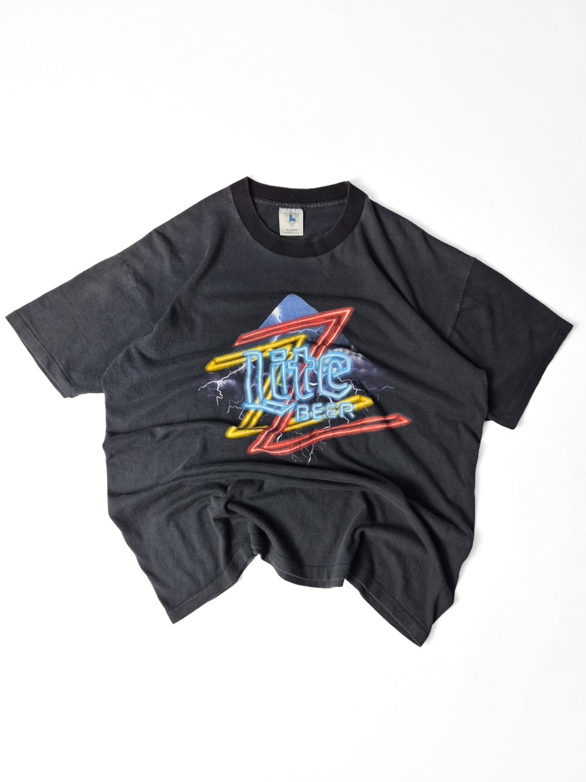 Faded zwart vintage Miller Lite T-shirt met een kleurrijke ZZ Top-neonprint en bliksemschichten op de voorkant.
