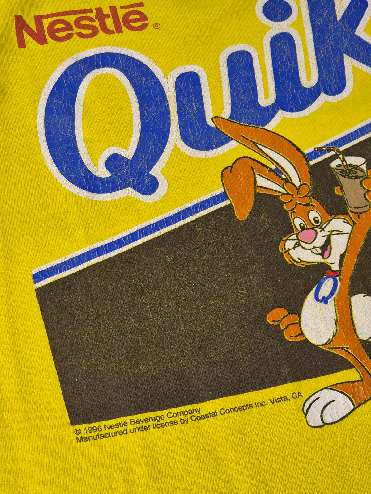 Detail van vintage Nestlé Quik T-shirt uit 1996 met Quicky Bunny graphic, craquelure en originele copyrightvermelding.
