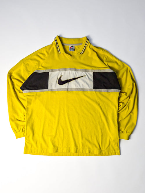 Vintage Nike rugby shirt uit de jaren 90 in geel met zwart-wit colorblock borstpaneel, lange mouwen en grote Center Swoosh.