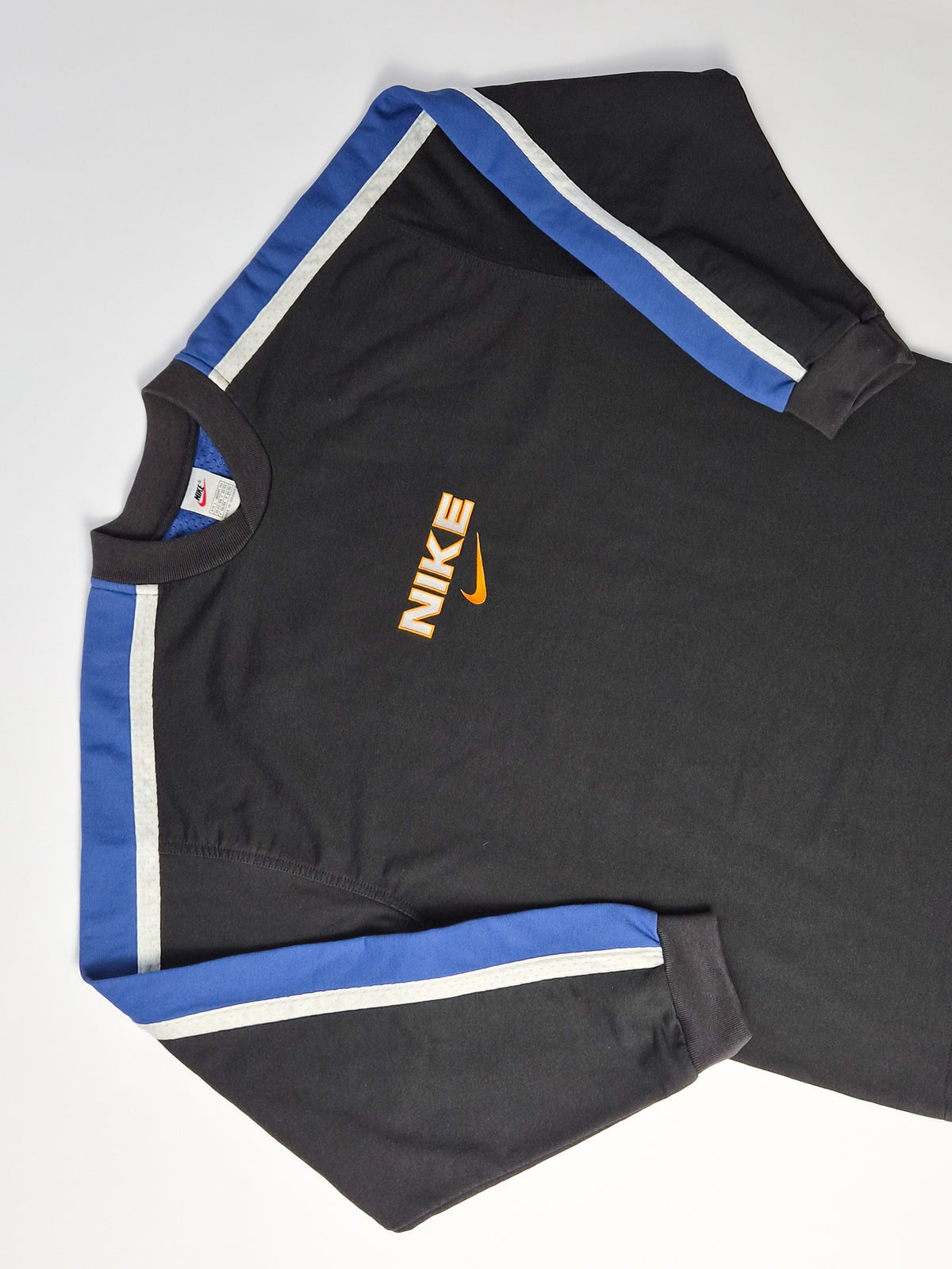 Zwarte vintage Nike sweater met Nike-naam, oranje Swoosh en blauw-witte banen over de schouders en mouwen van dichtbij.