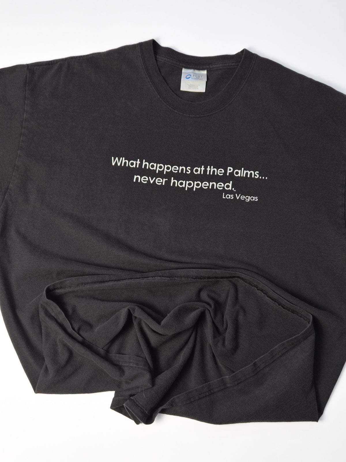Vintage Palms Las Vegas T-shirt uit circa 2005 in faded zwart met minimalistische witte sloganprint, los neergelegd.