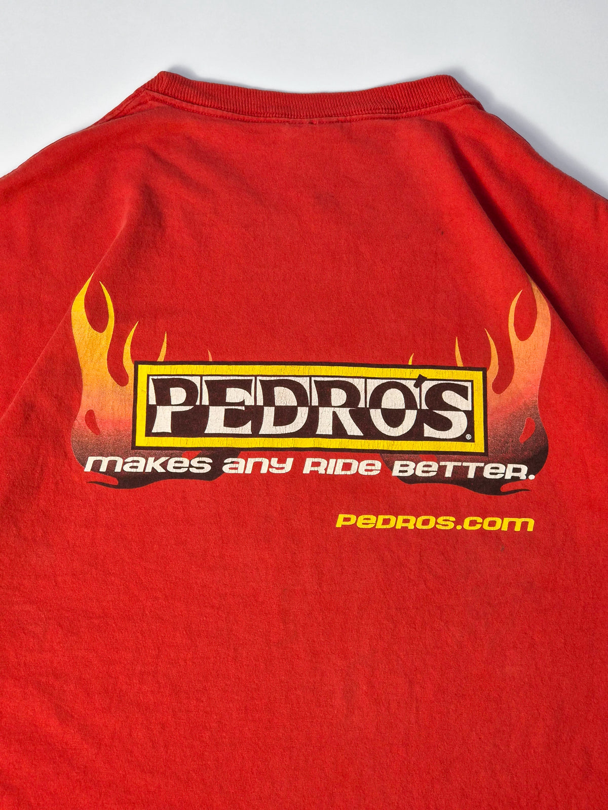 Rood vintage Pedro’s mountainbike T-shirt uit circa 2000 met grote flame backprint, Makes Any Ride Better slogan en pedros.com.