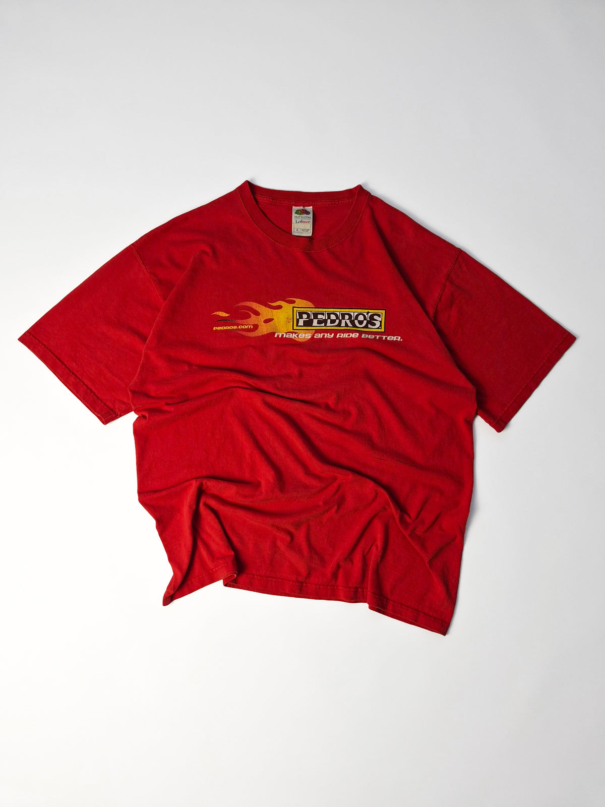 Vintage Pedro’s cycling graphic tee uit de vroege 2000s in rood met Y2K flame print, brede fit en Fruit of the Loom Lofteez blank.