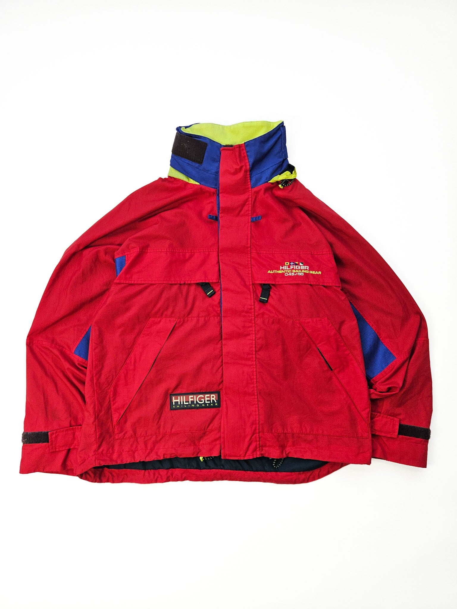 1990s Tommy Hilfiger Sailing Gear vintage jas in rood met blauwe en gele panelen en neon capuchon, vooraanzicht flatlay