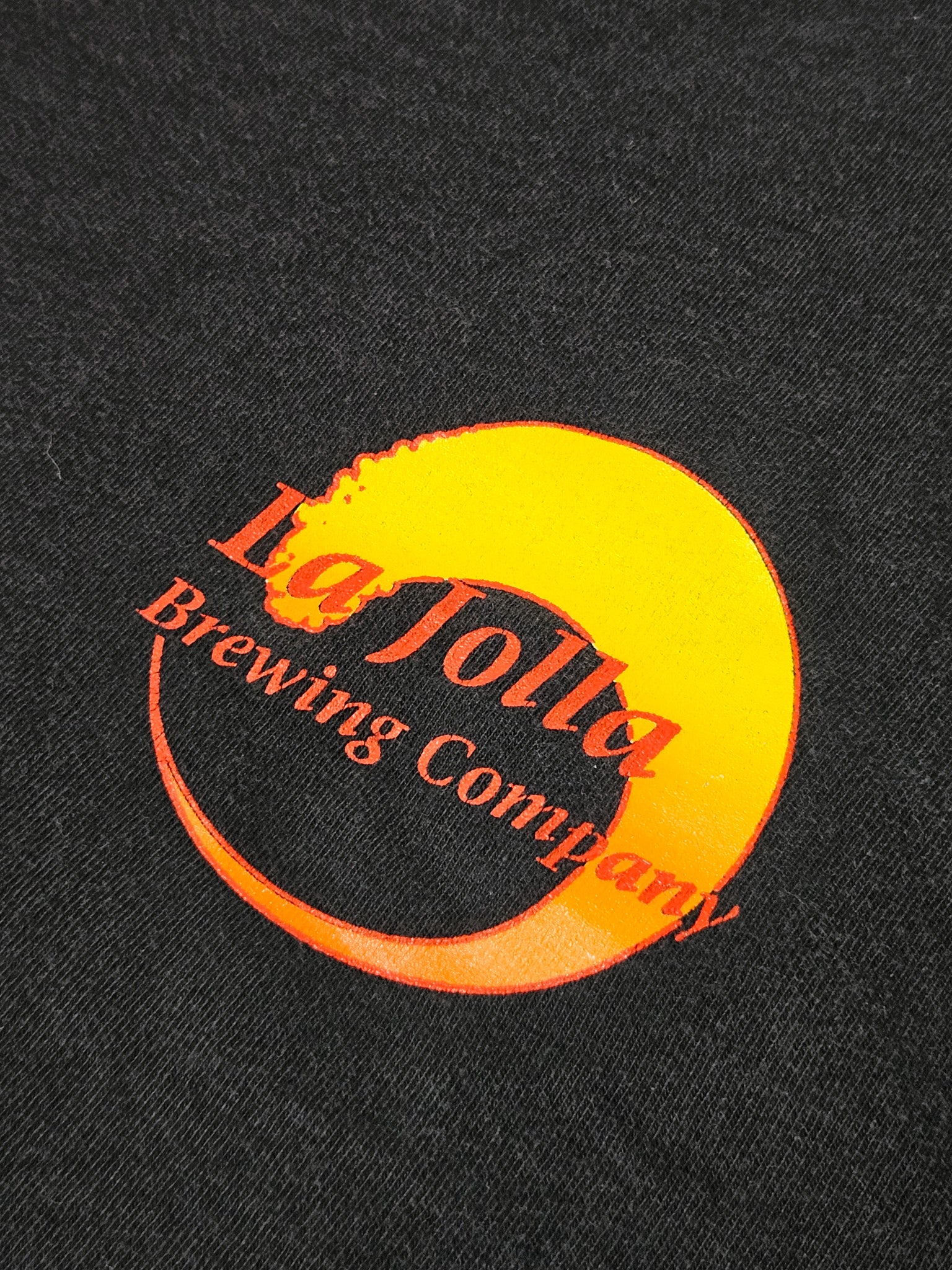 Close-up van het Red Jolt's Brewing Company logo op vintage T-shirt met zon en golf motief