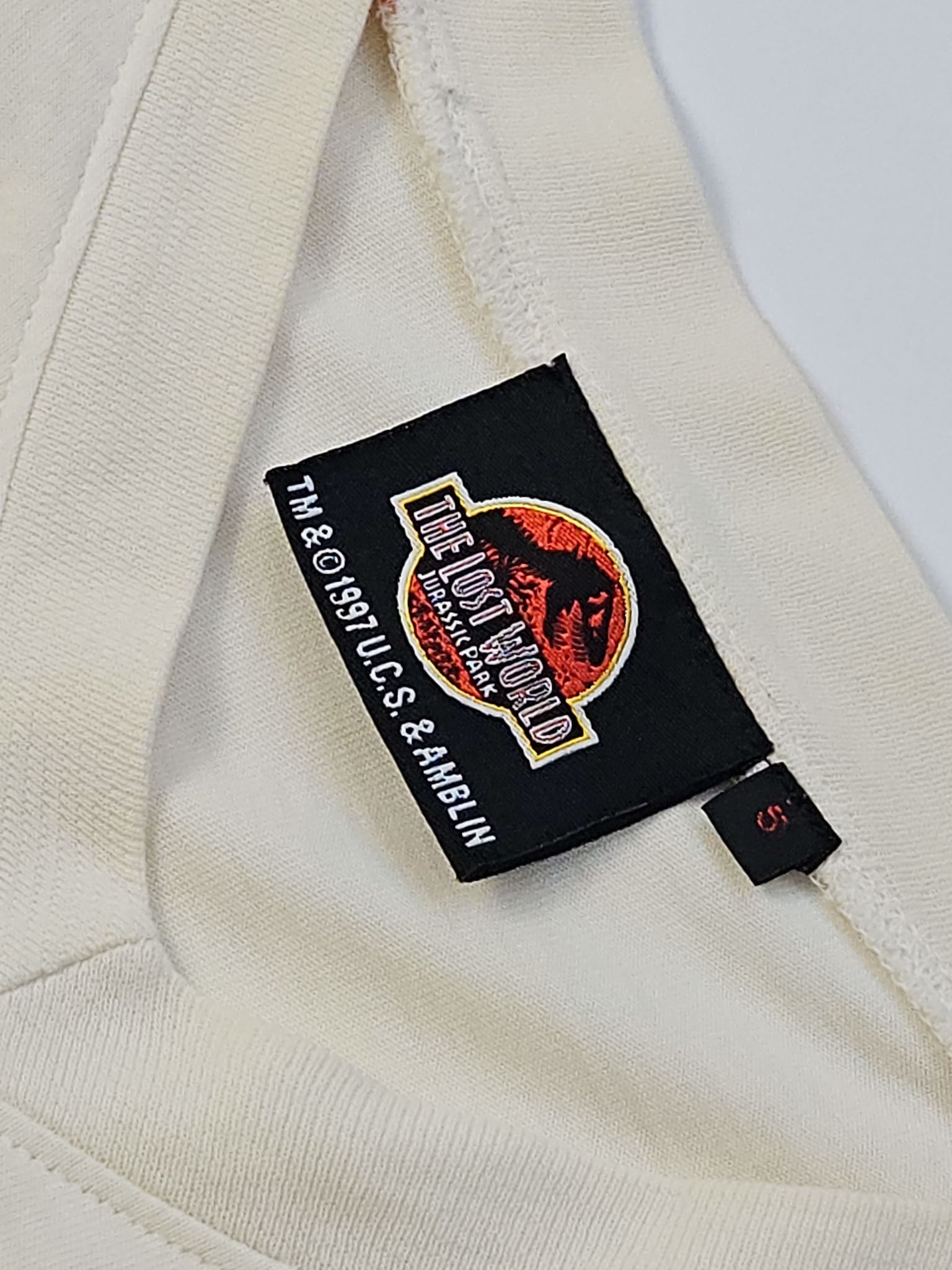 The Lost World branded halslabel met 1997 U.C.S. en Amblin copyright en maataanduiding S